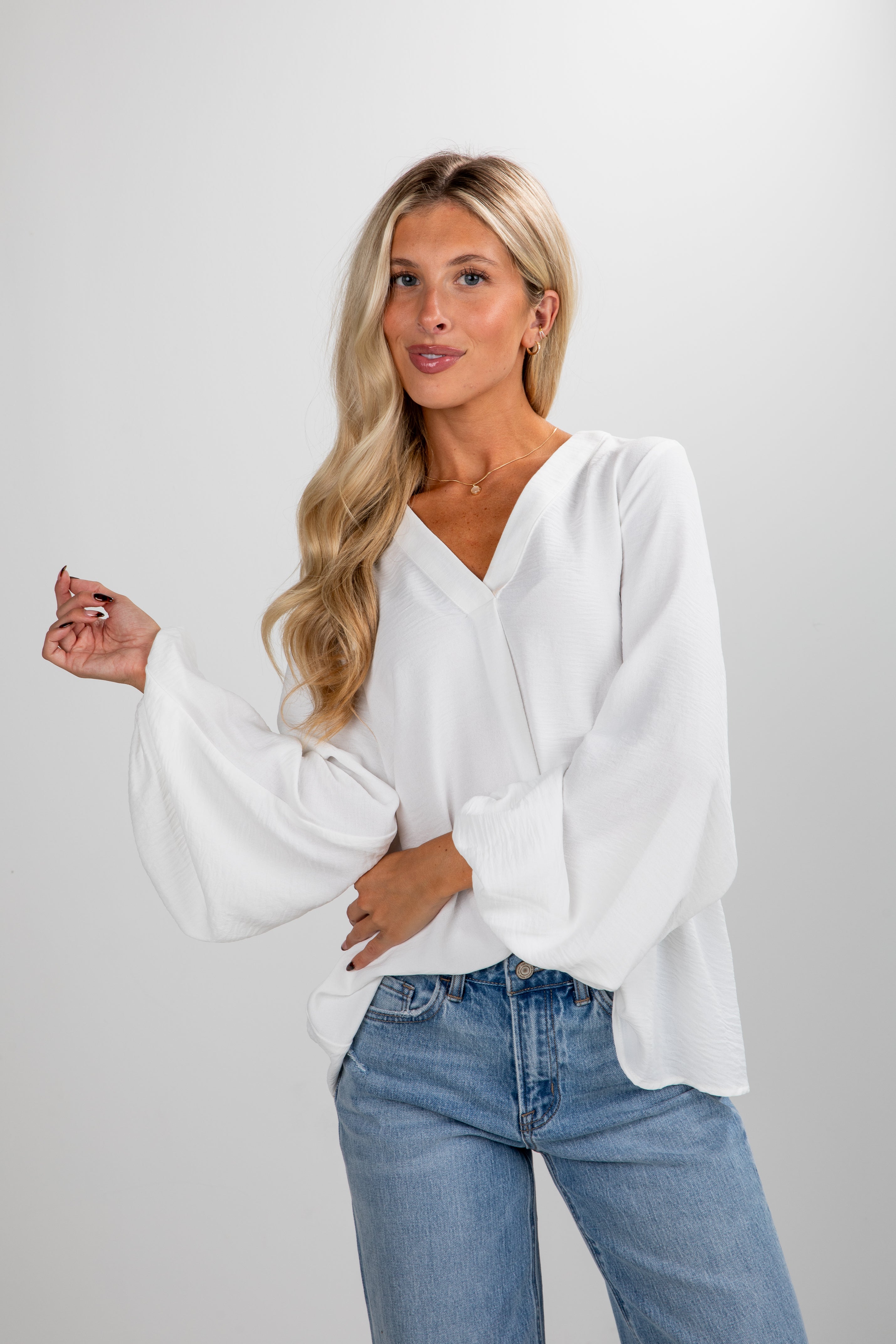 Woman wearing a white blouse and blue jeans on a plain background