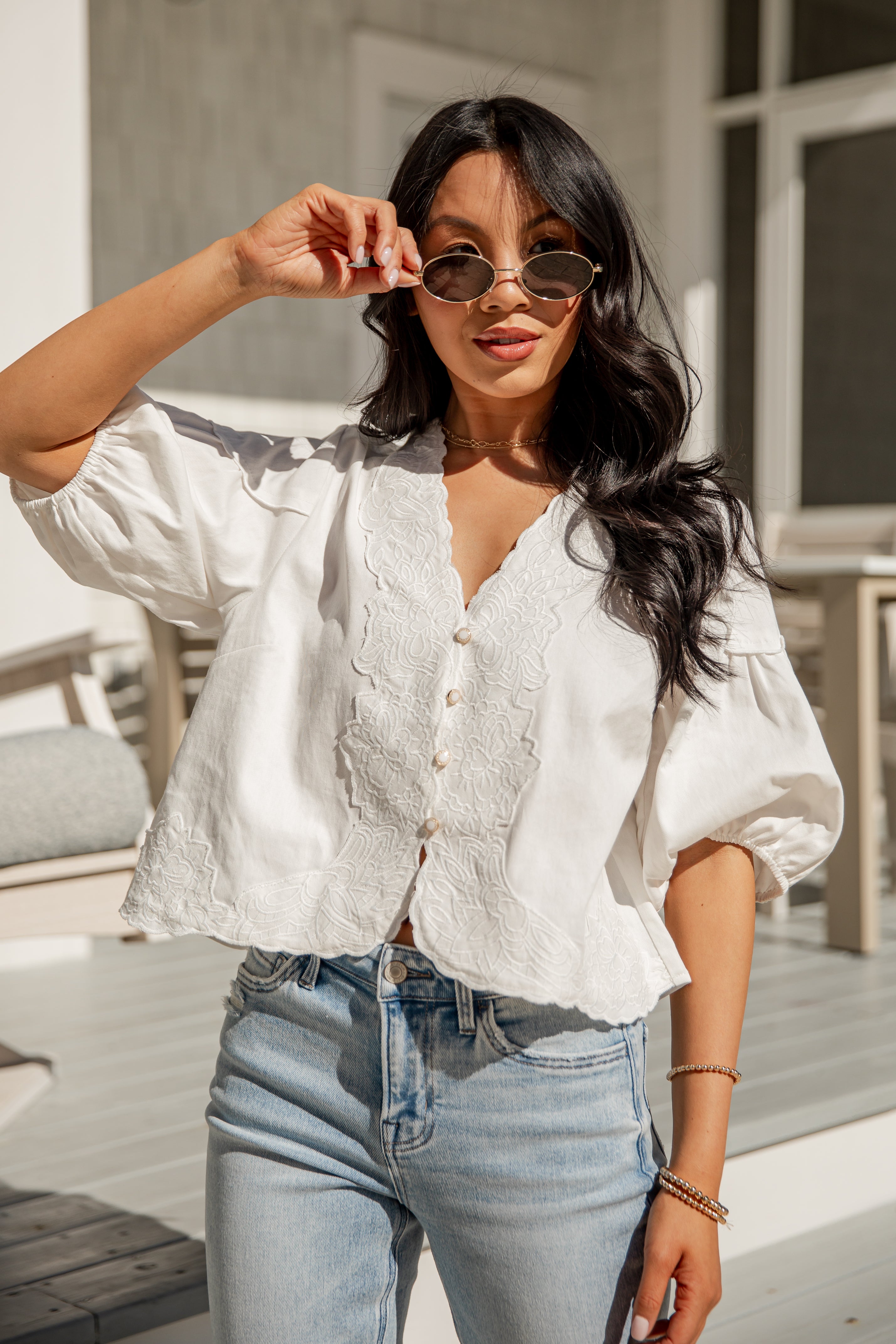 Woman wearing a white blouse and blue jeans outdoors