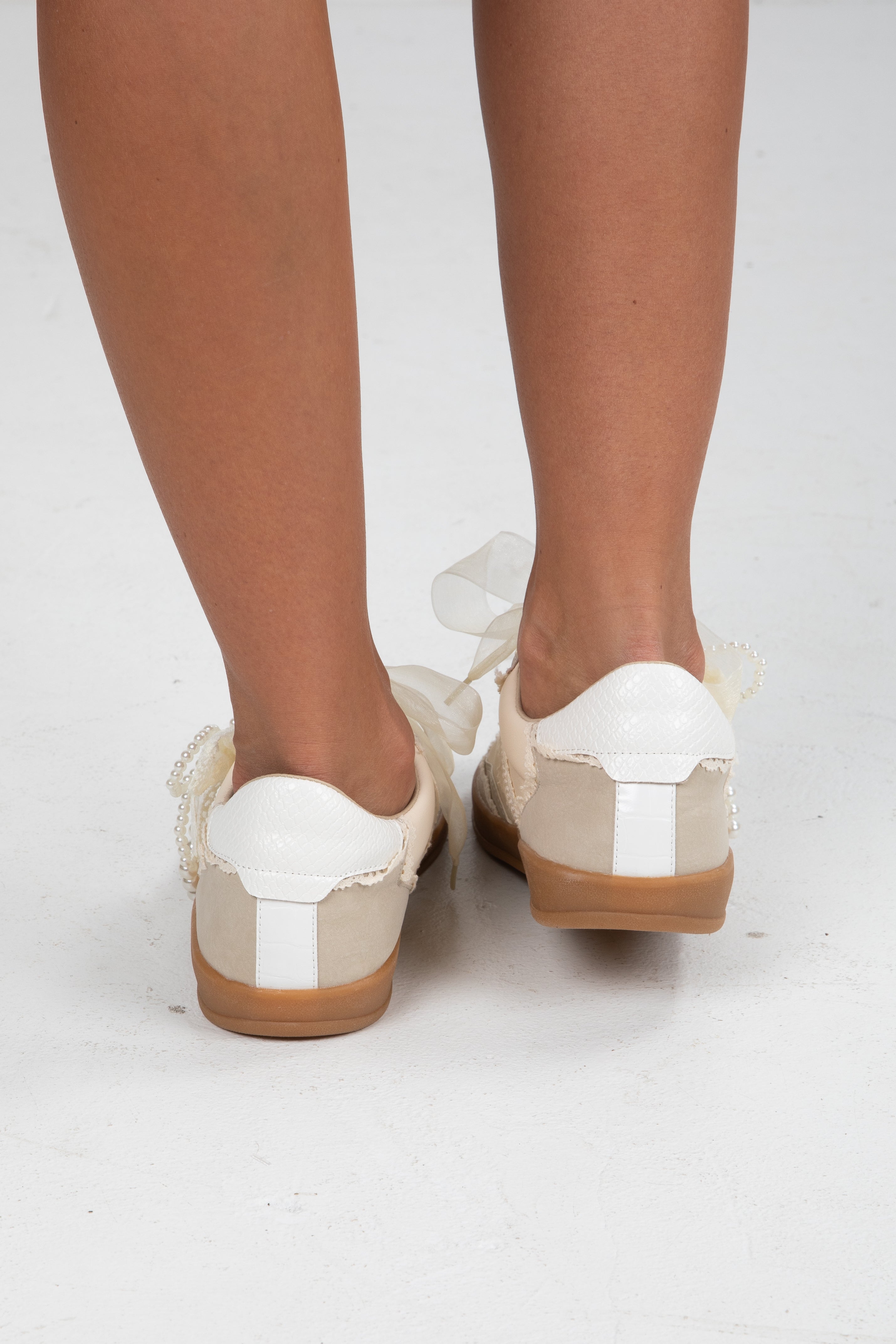 White and brown shoes worn by a person on a white background