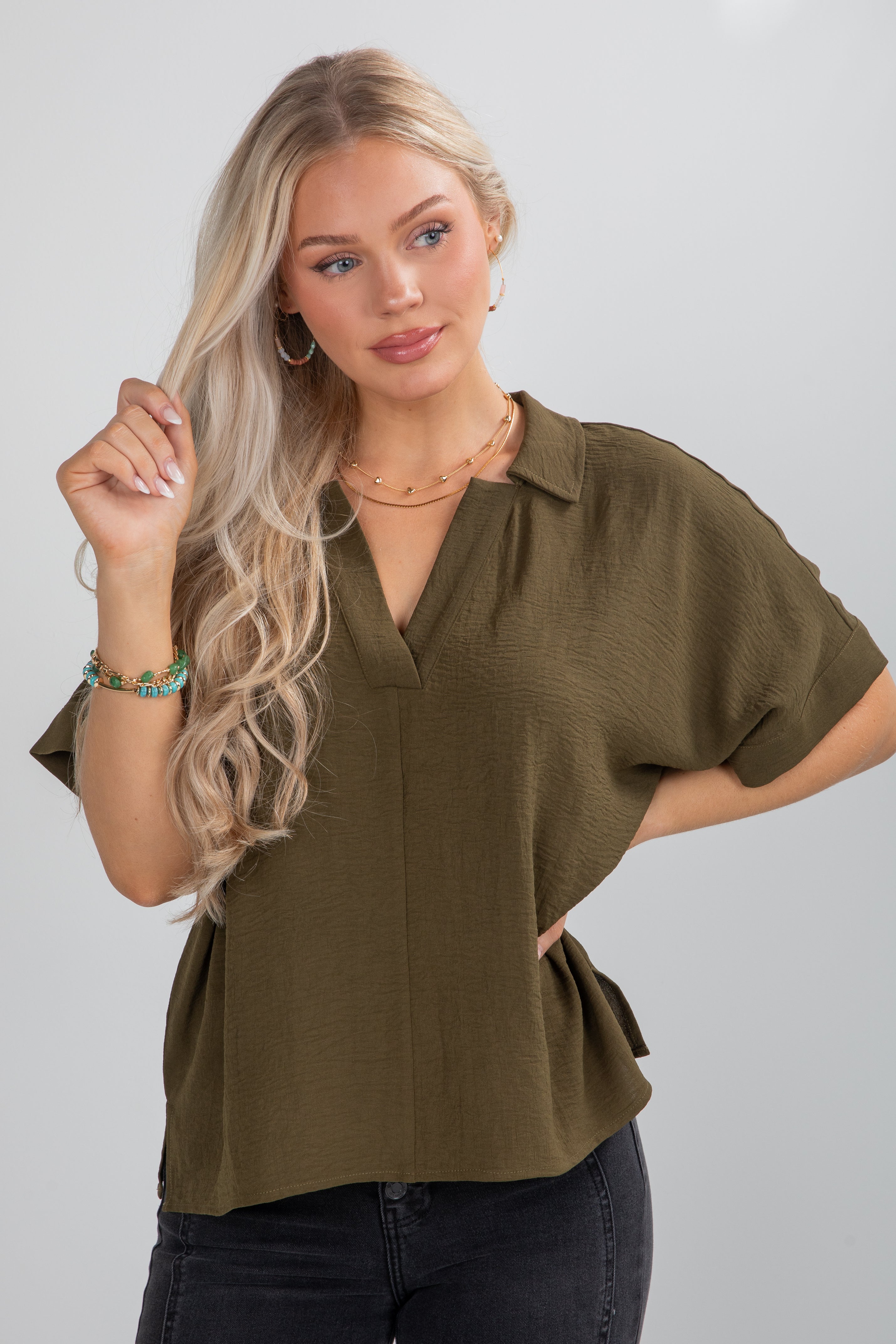 Woman wearing an olive green blouse against a plain background