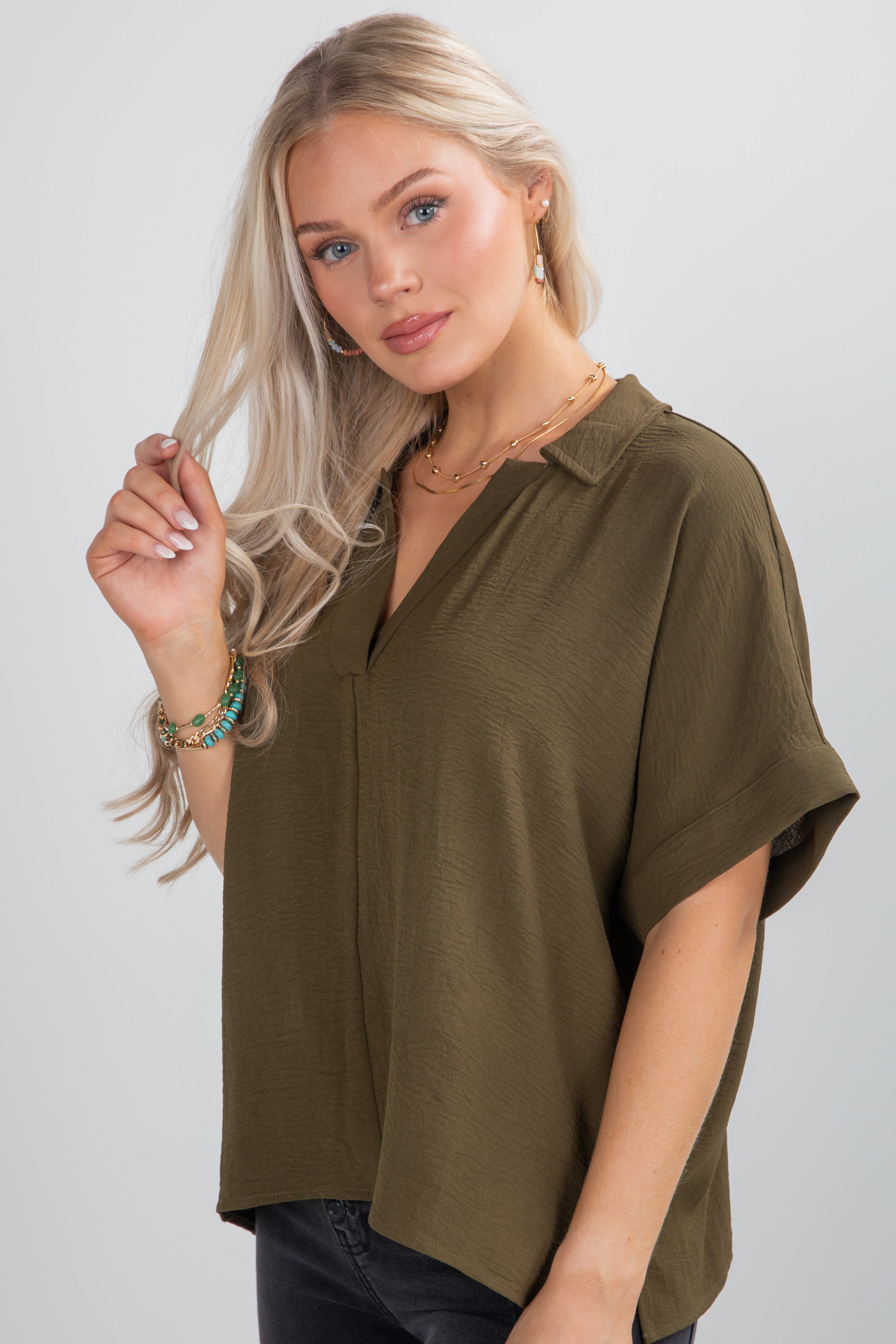 Woman wearing an olive green blouse against a plain background
