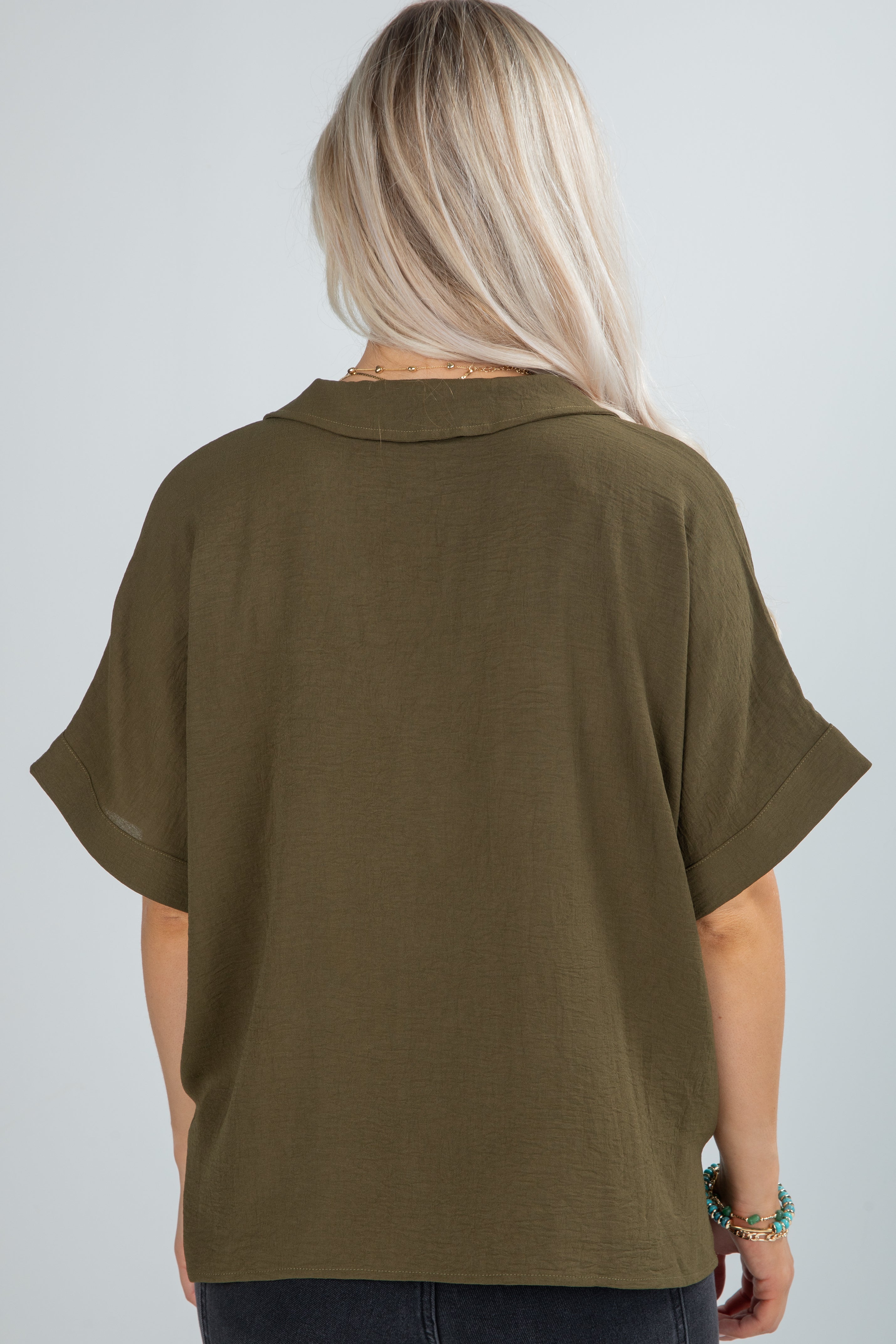 Person wearing an olive green shirt on a plain background