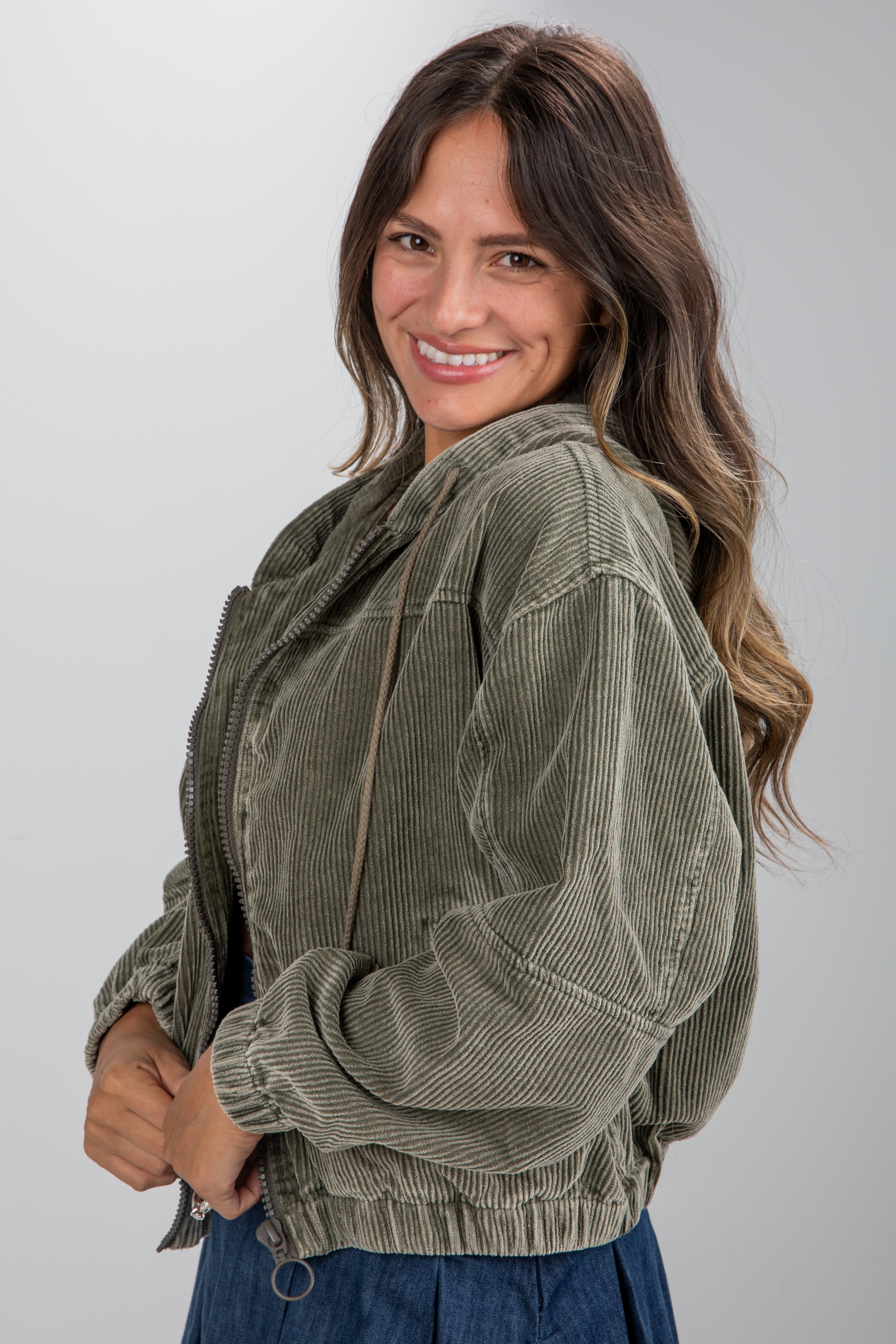 Woman wearing a green corduroy jacket against a plain background