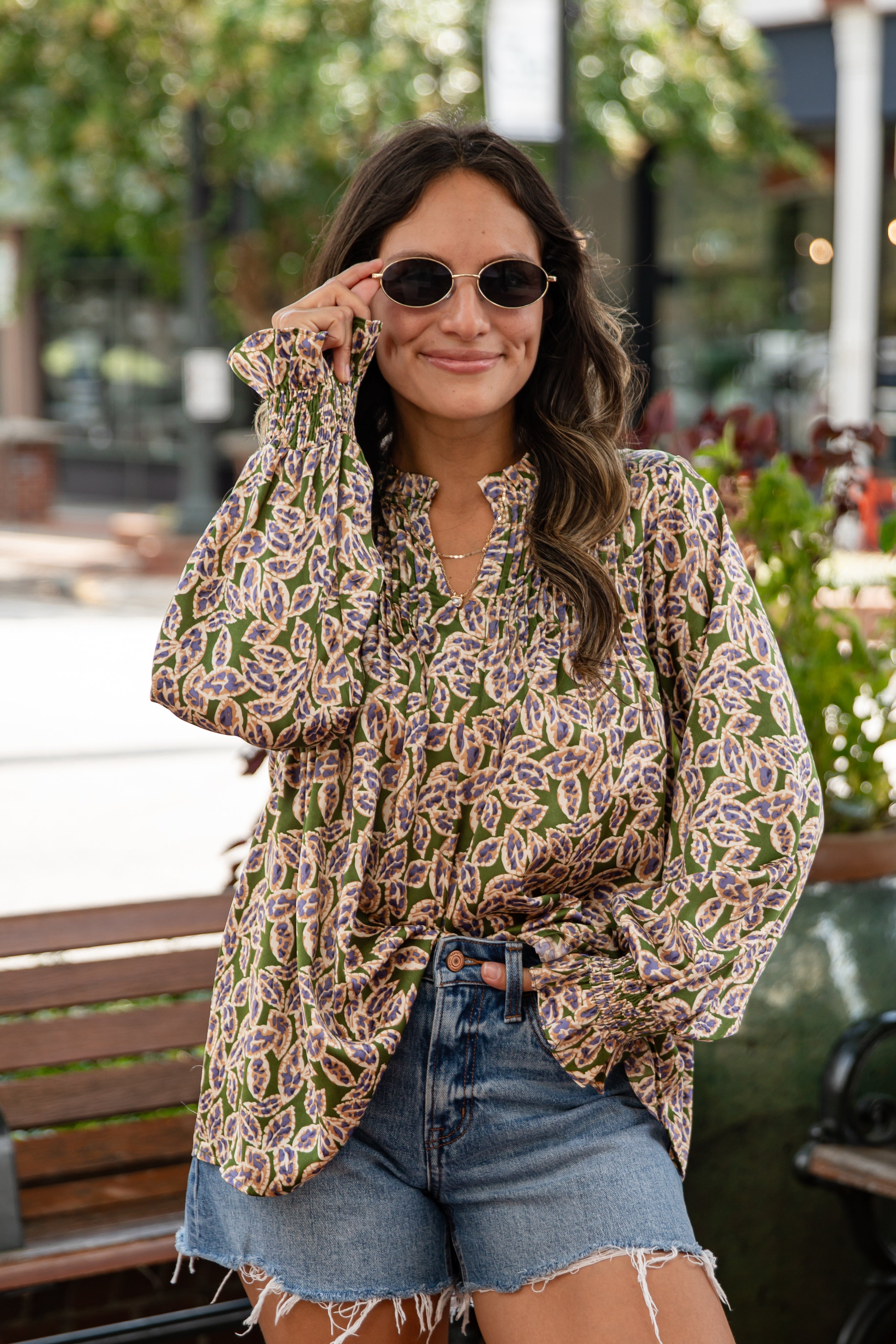 Woman wearing a patterned shirt and denim shorts outdoors