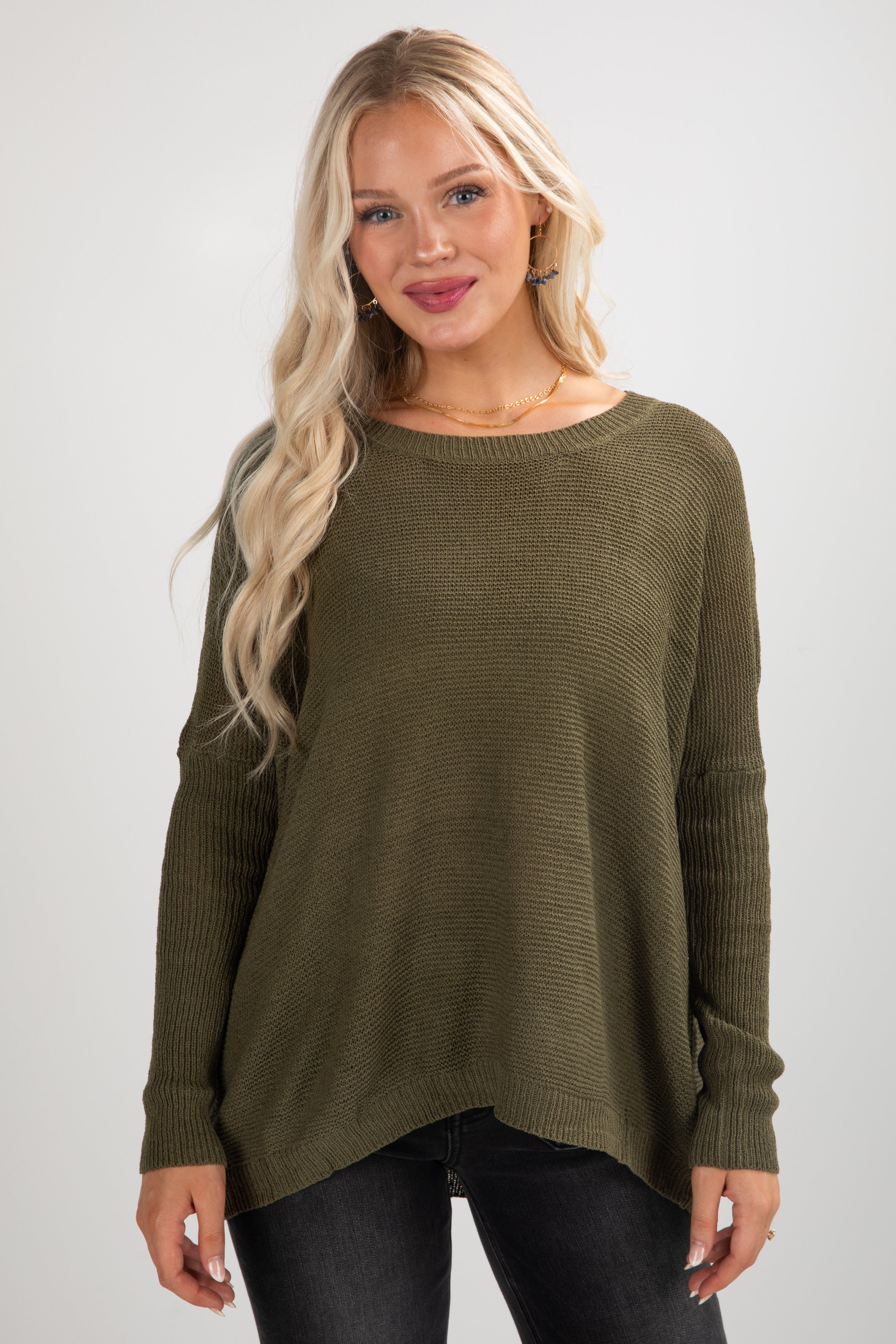 Woman wearing an olive green sweater against a white background