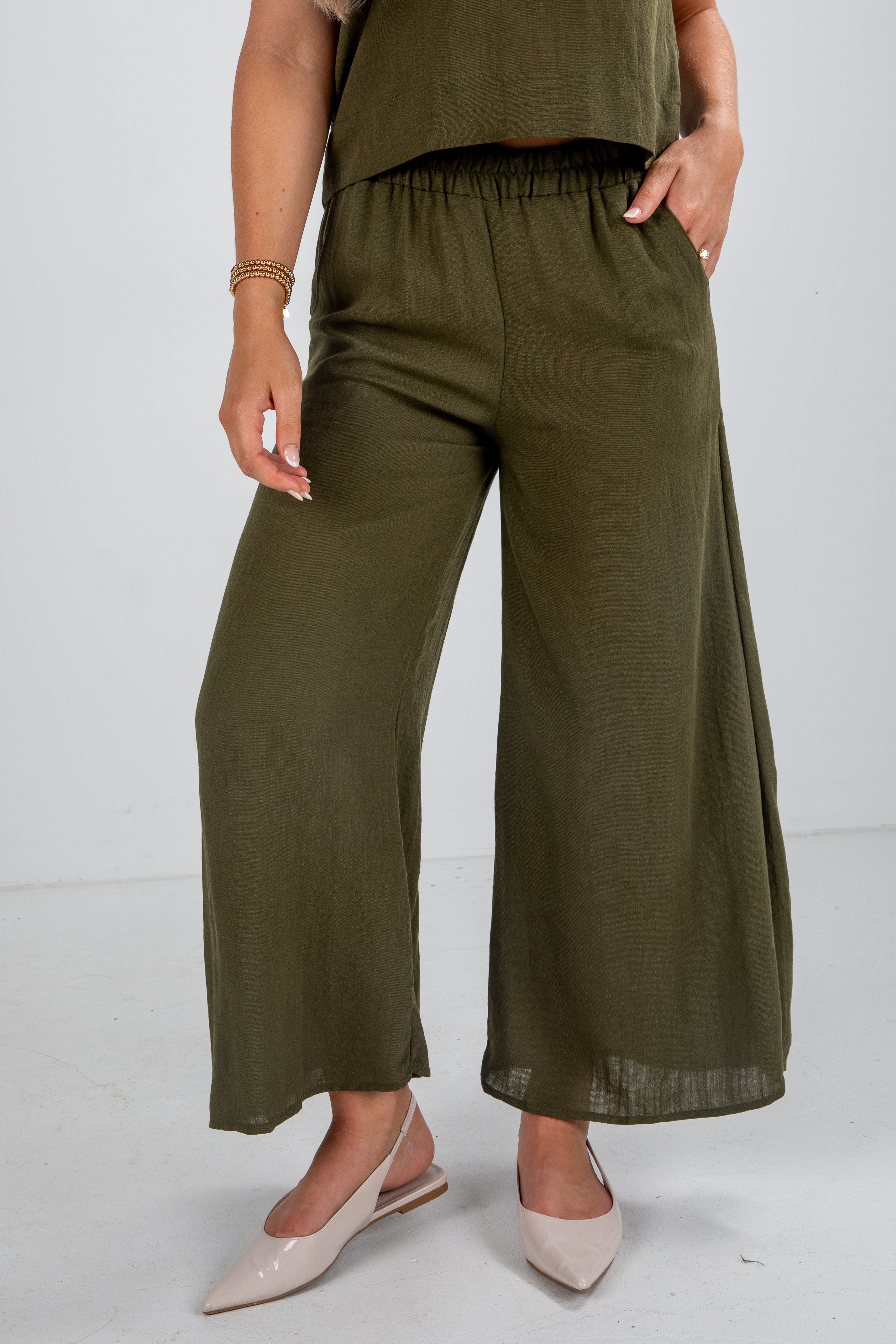 Person wearing olive green wide-leg pants on a white background