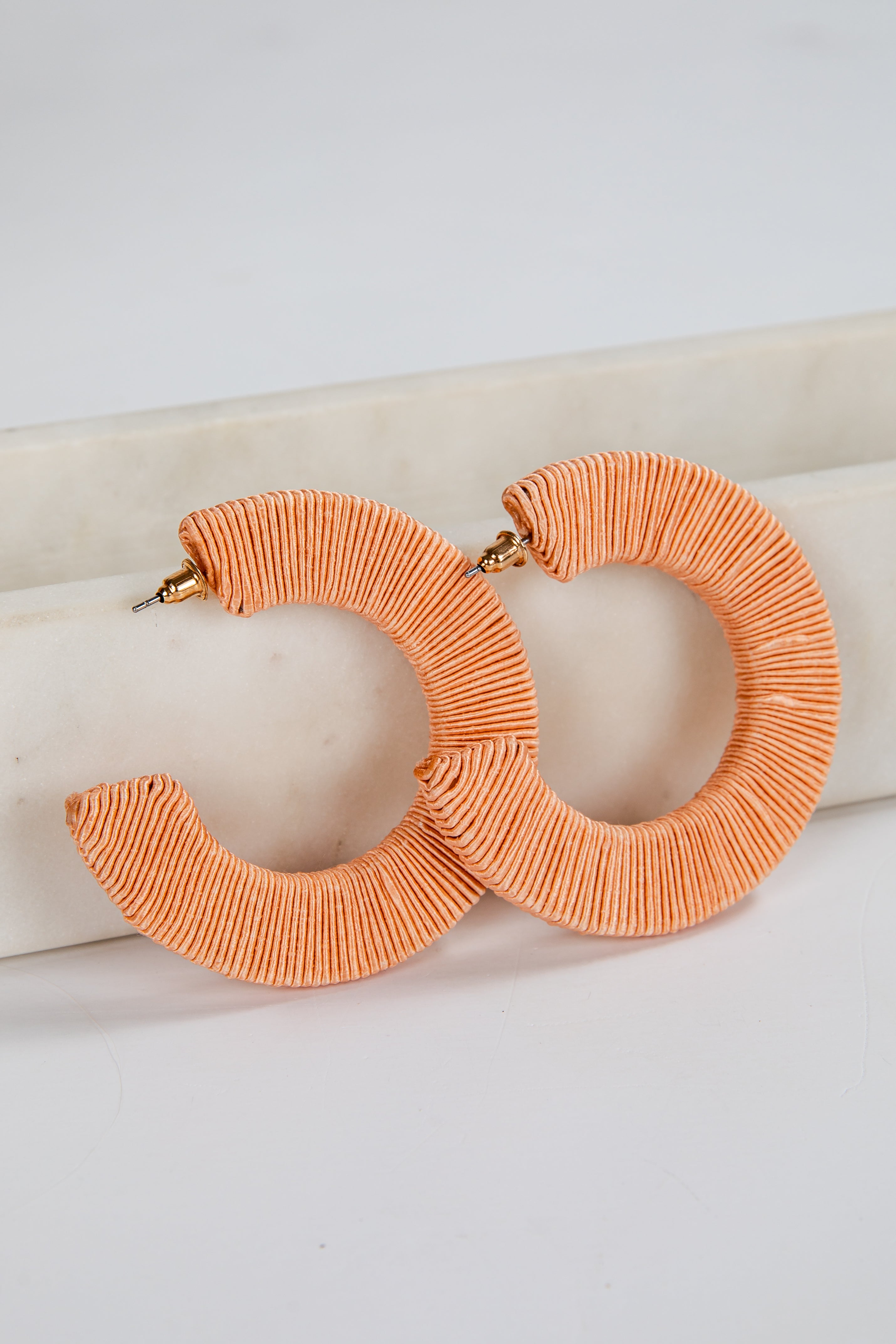Pair of orange hoop earrings on a white surface