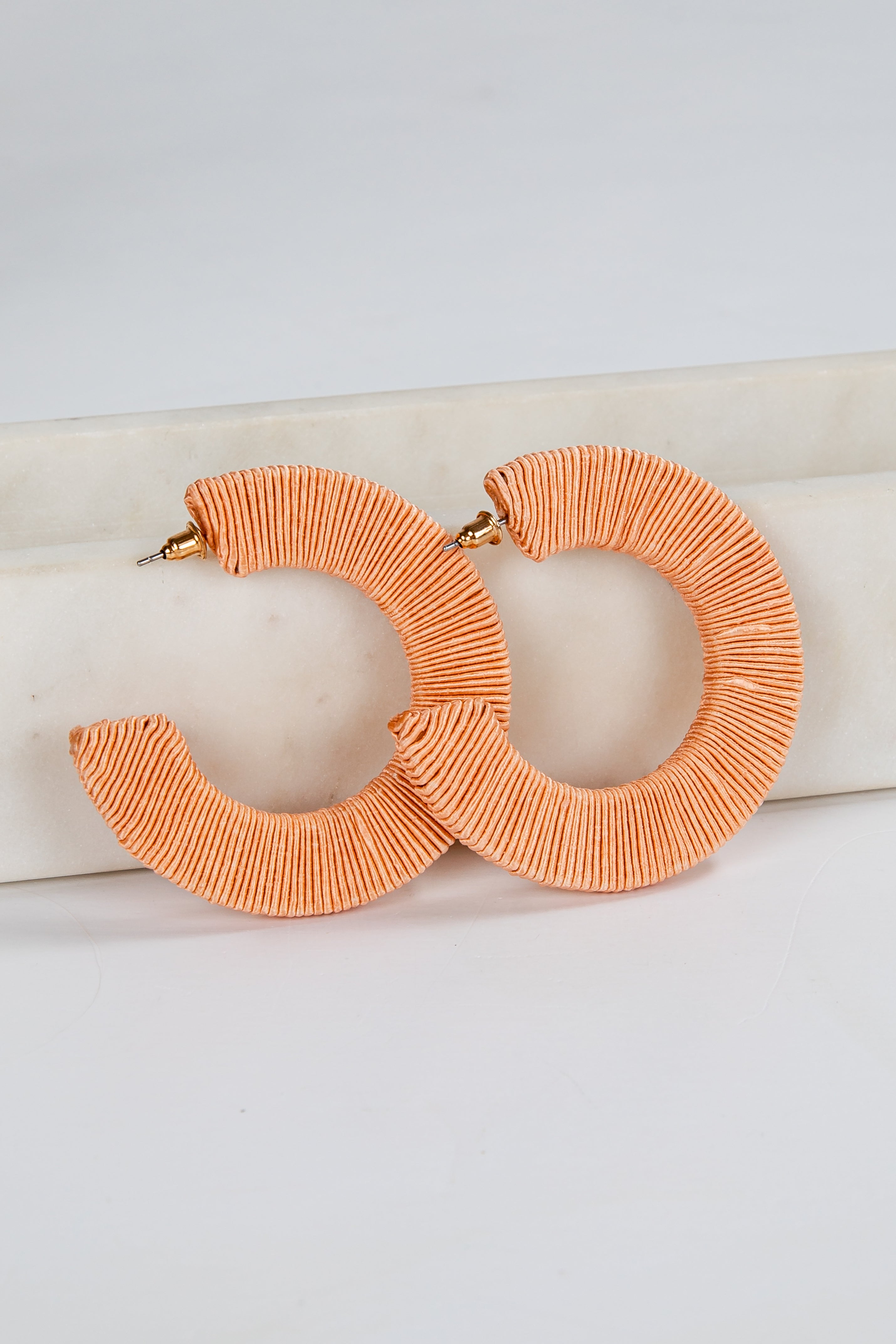 Pair of orange hoop earrings on a light background