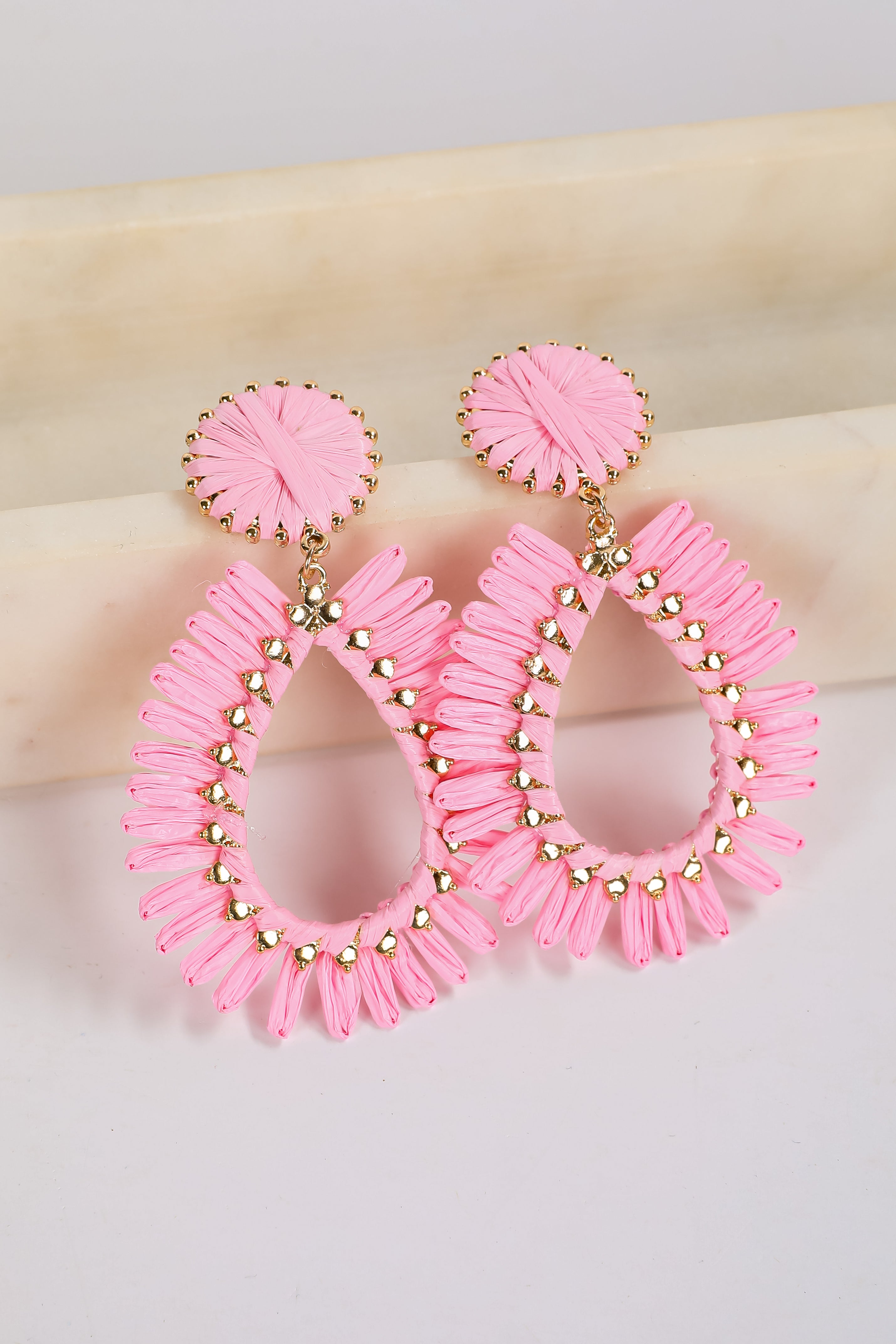 Pink hoop earrings with gold accents on a light background