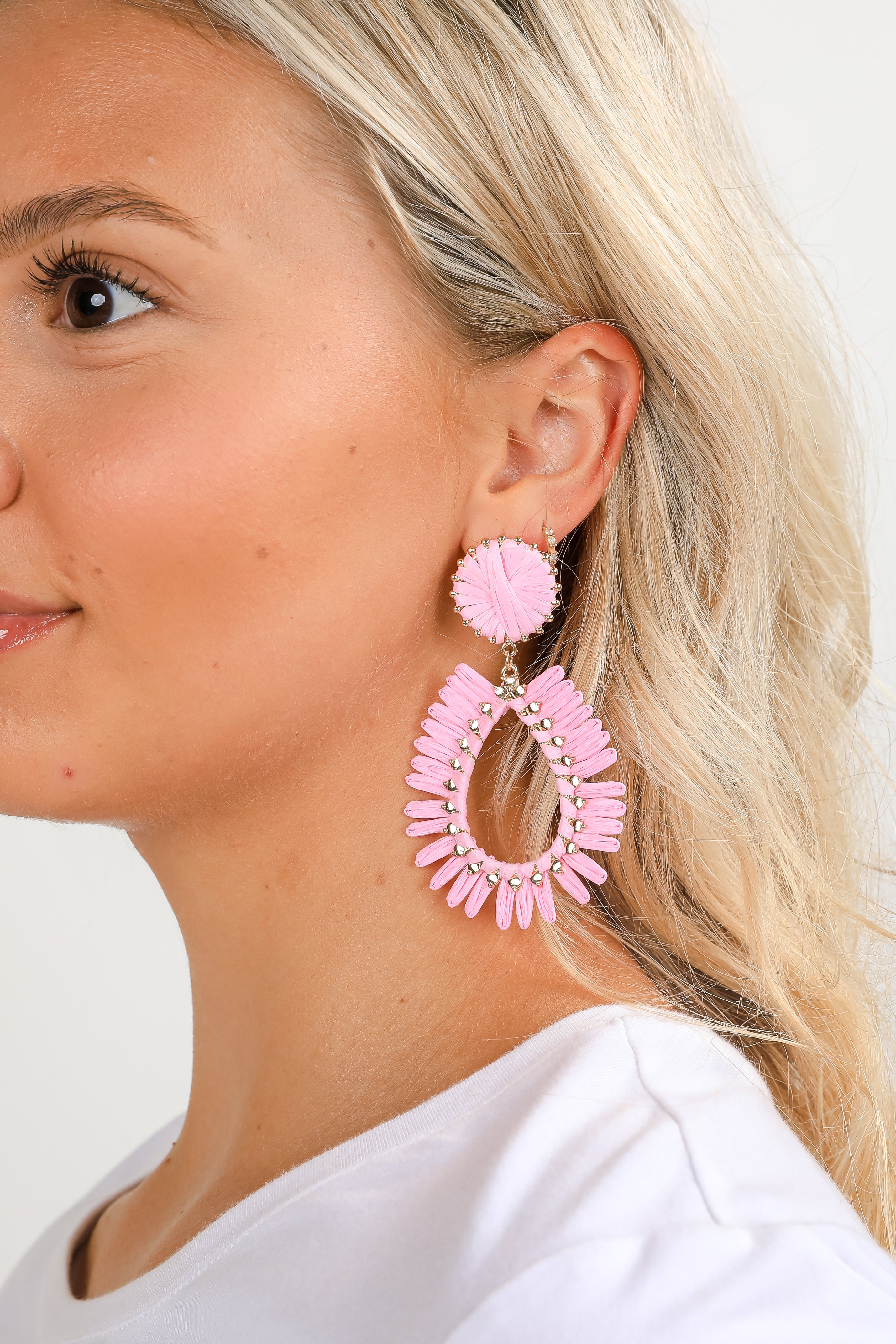 Close-up of a person wearing pink hoop earrings with a blurred background