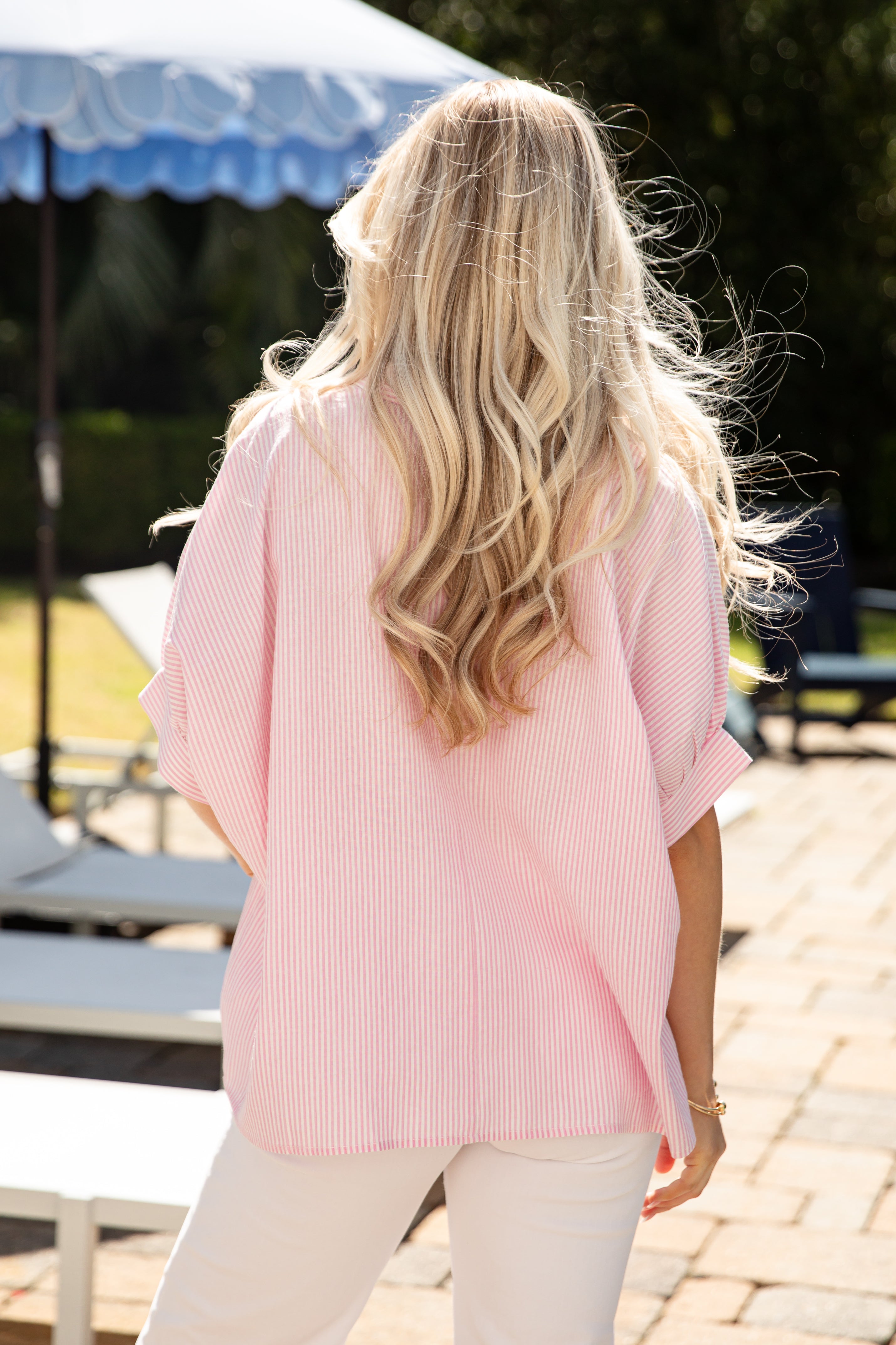 Person wearing a pink blouse with a blurred outdoor background
