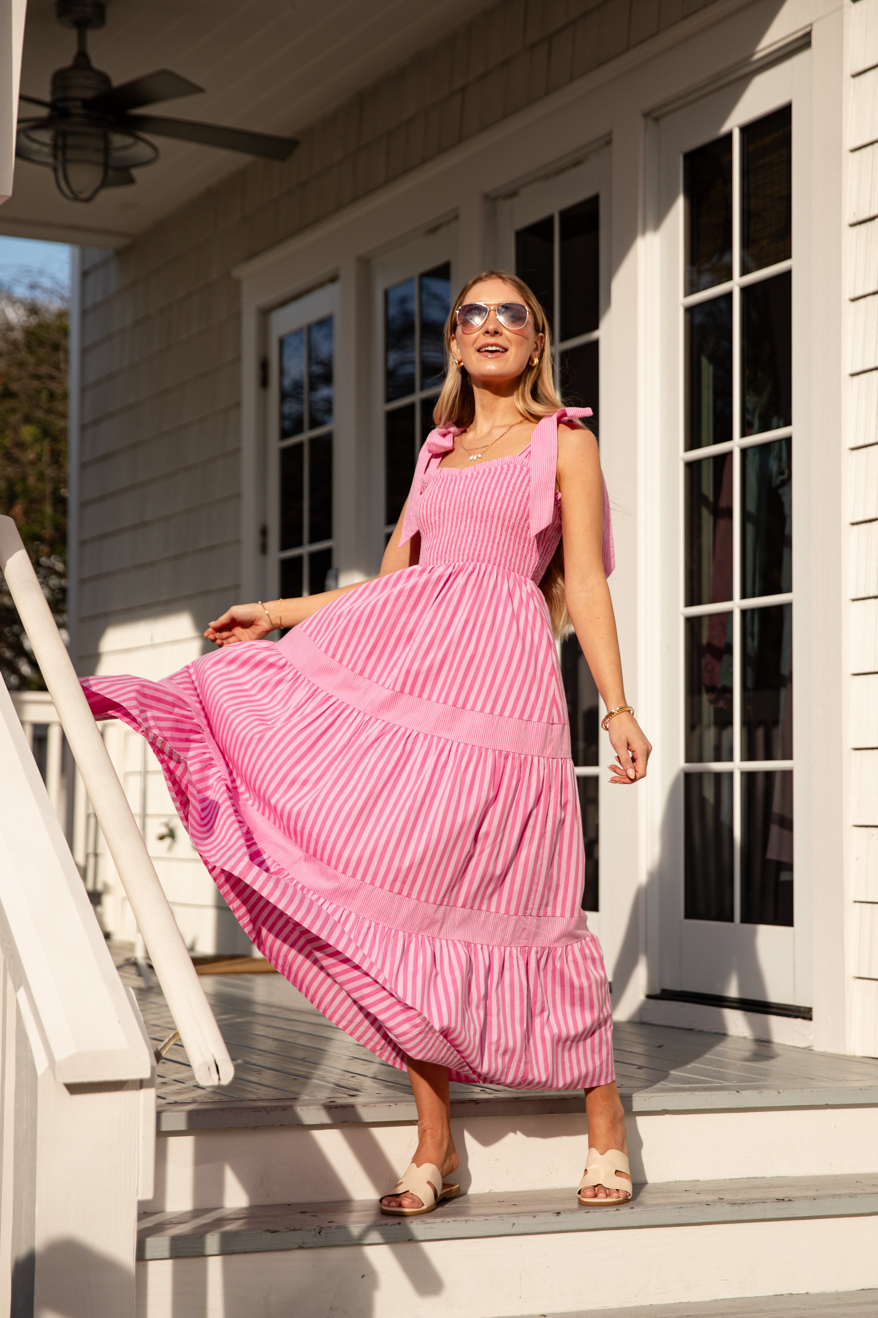 Woman in a pink dress standing on a porch