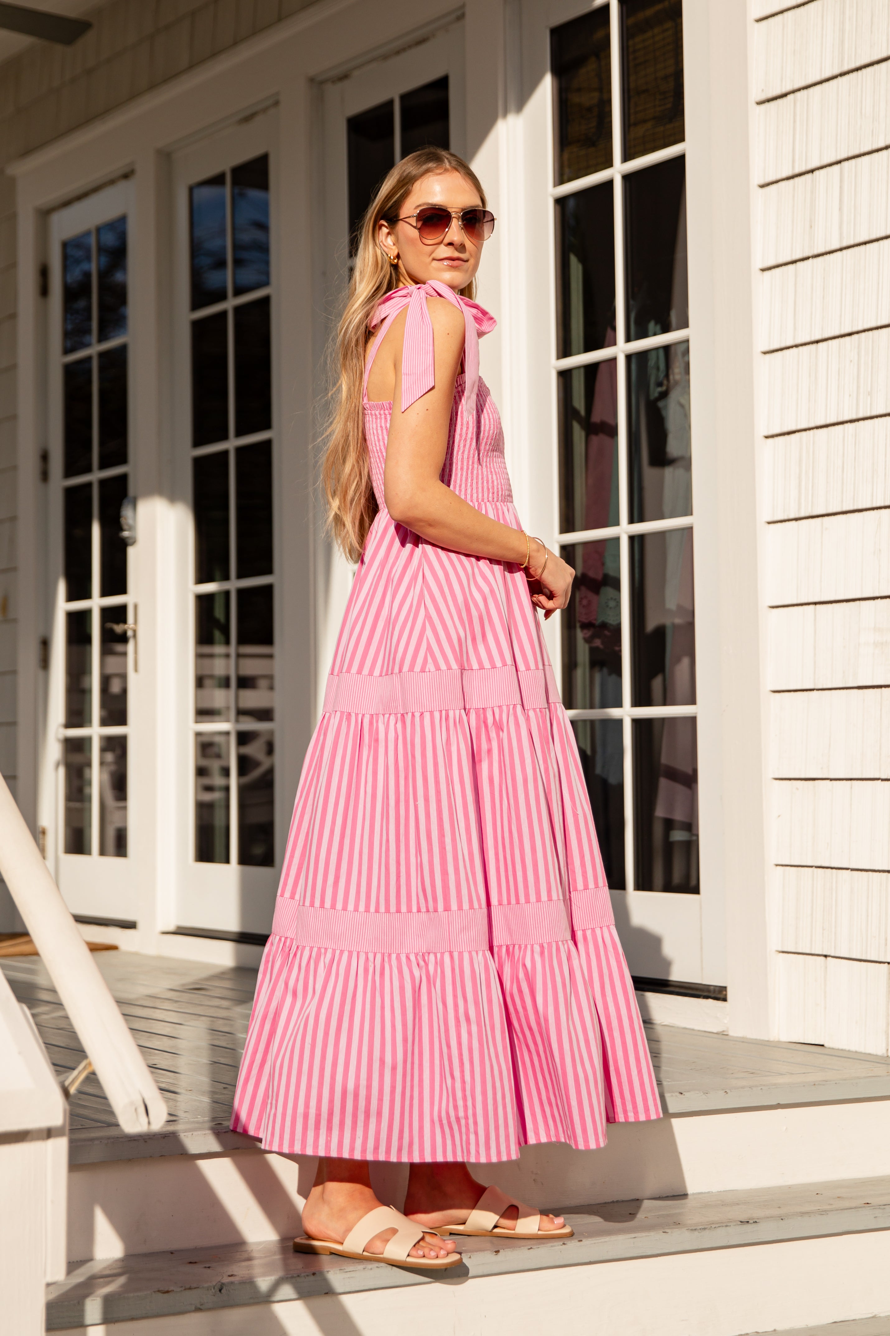 Woman in a pink dress standing on a porch