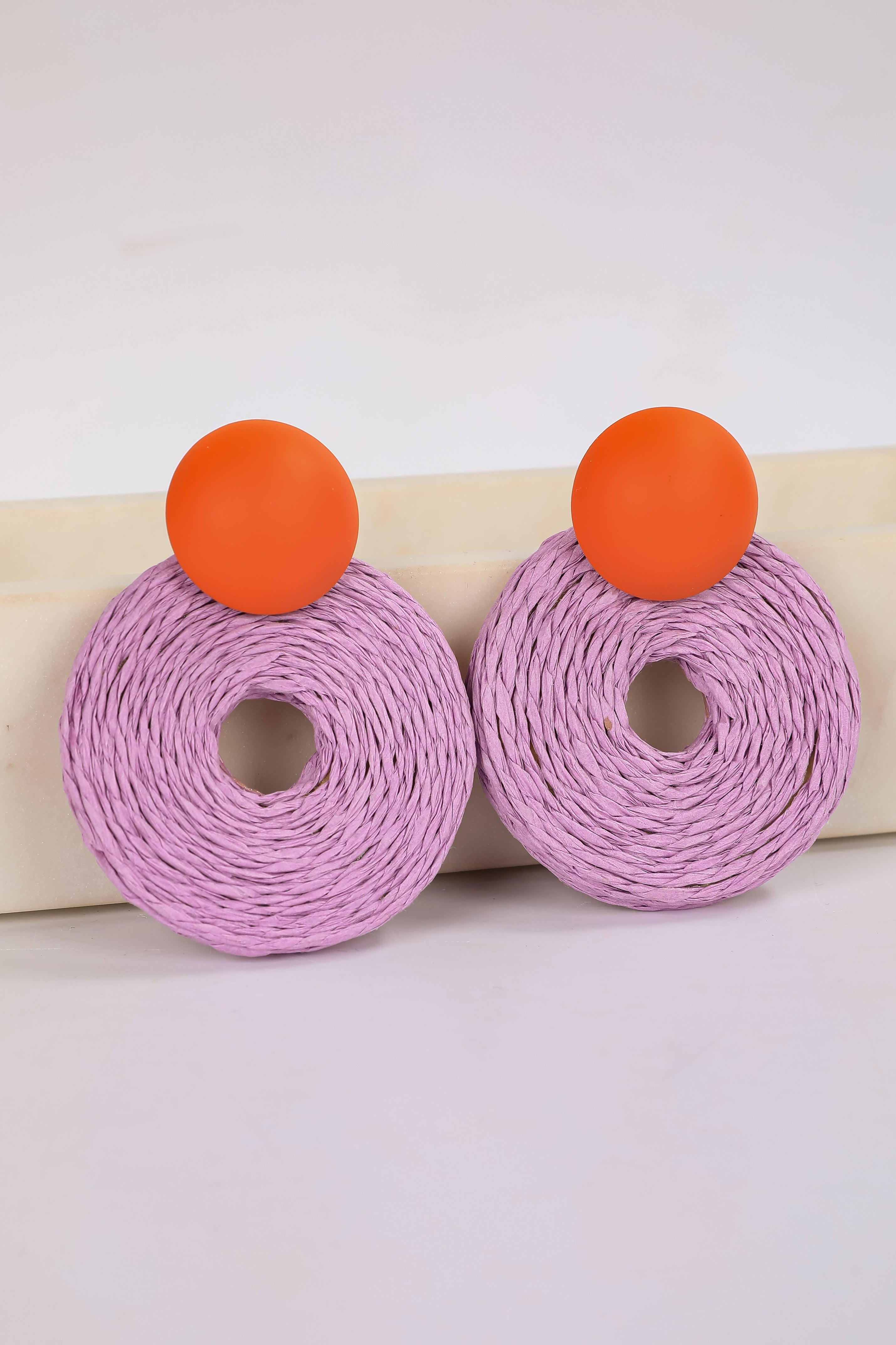 Pair of earrings with purple circular designs and orange accents on a white background