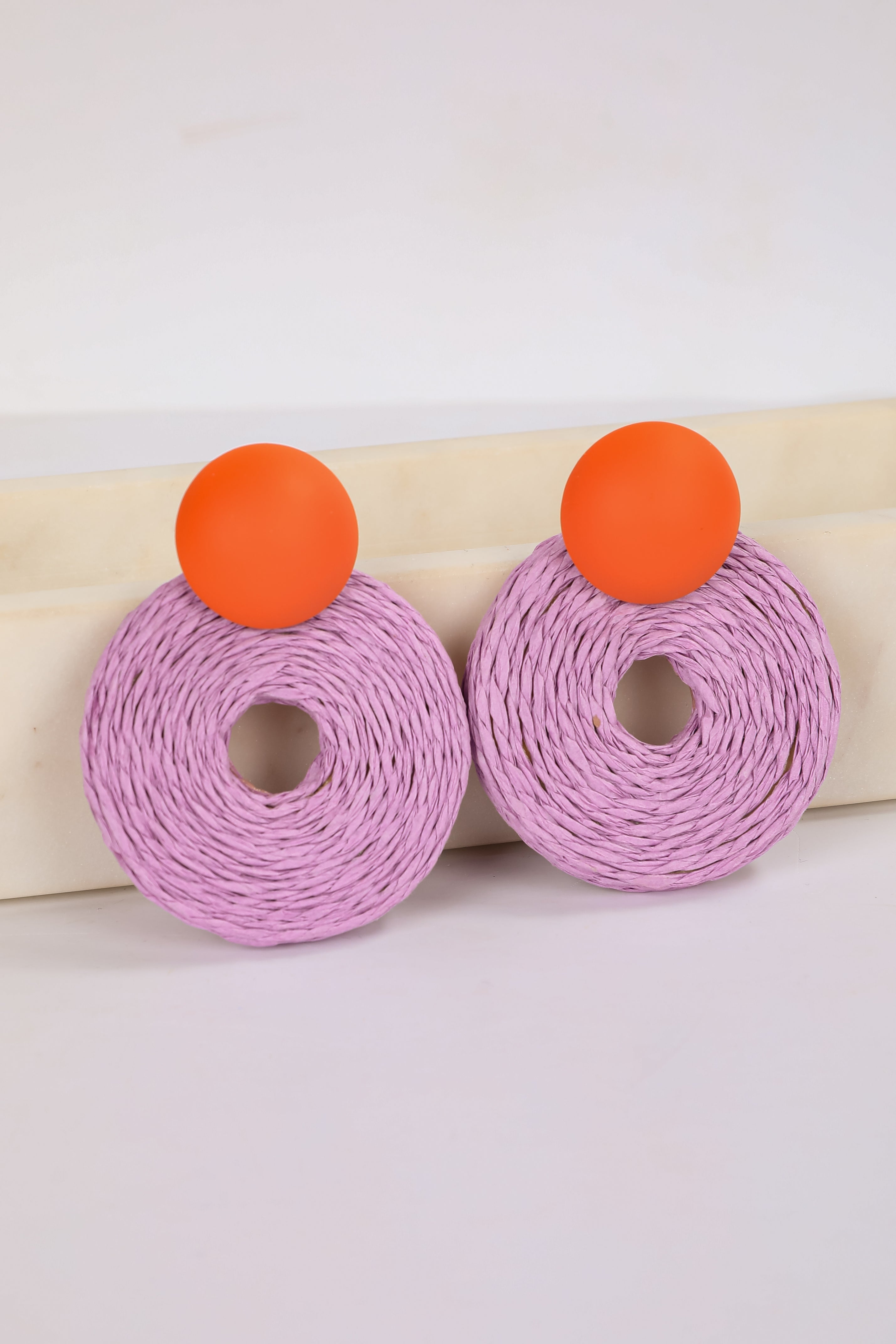 Pink earrings with orange tops on a white background