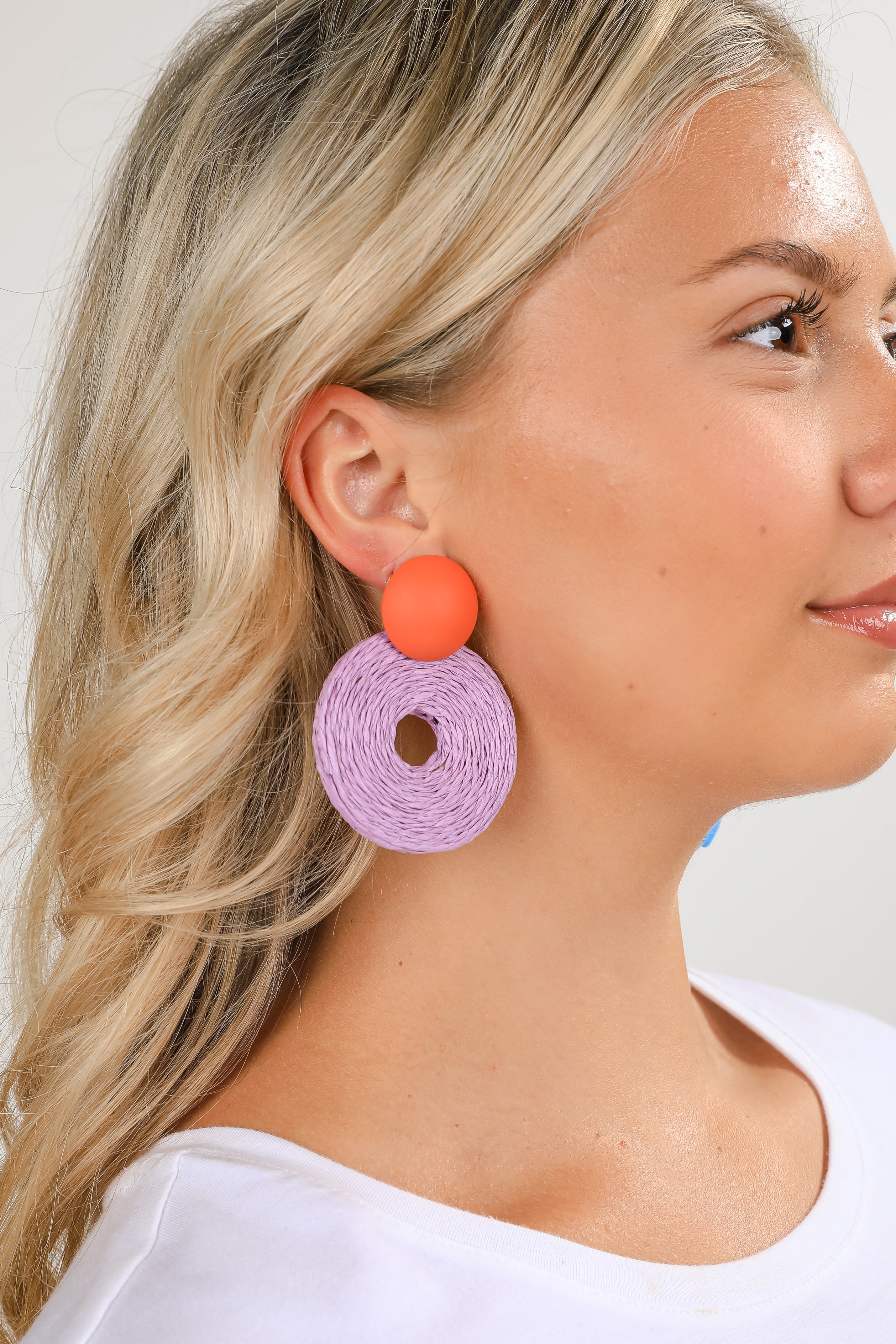 Woman wearing colorful earrings with a plain background