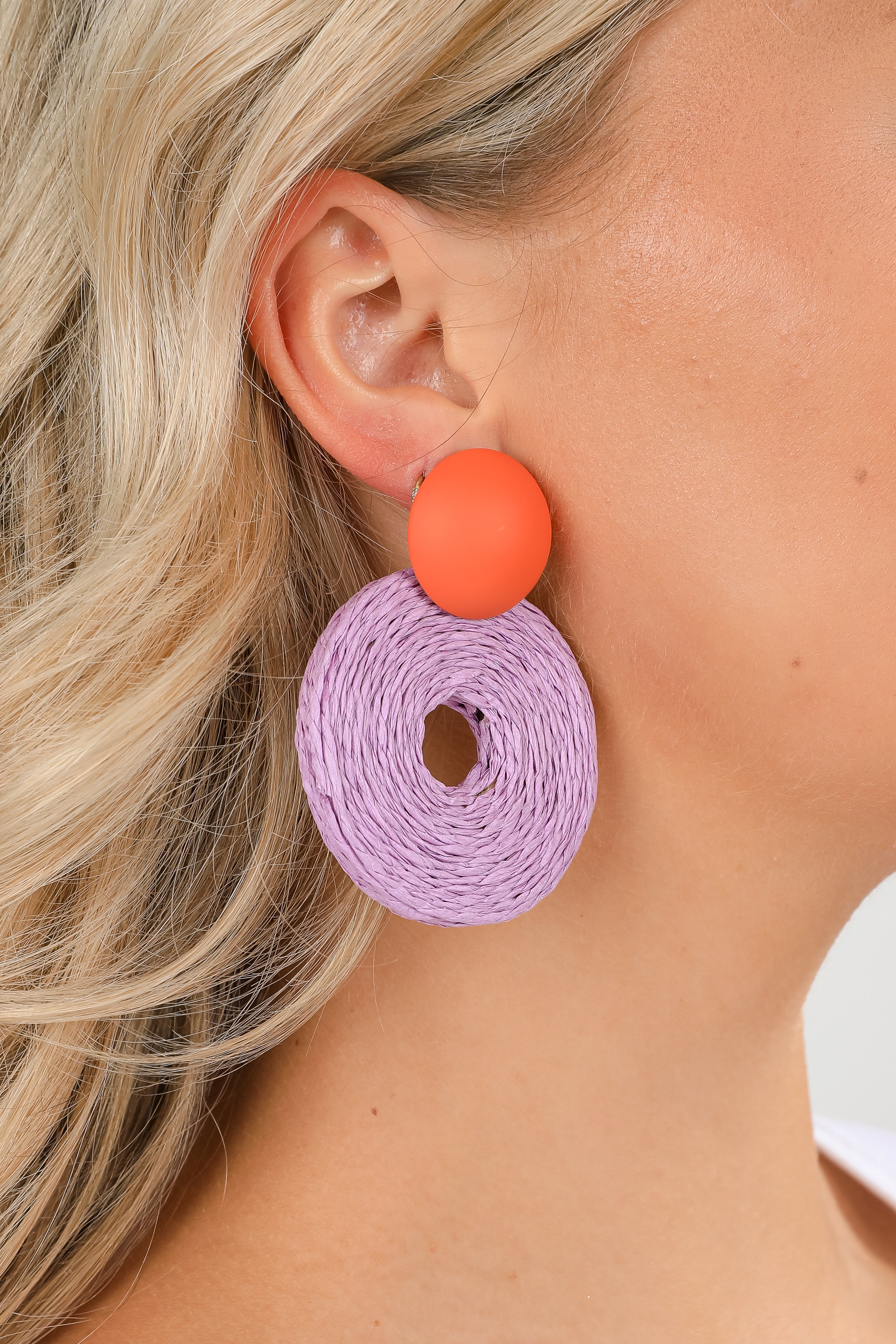 Close-up of a person wearing a pink and orange earrings.