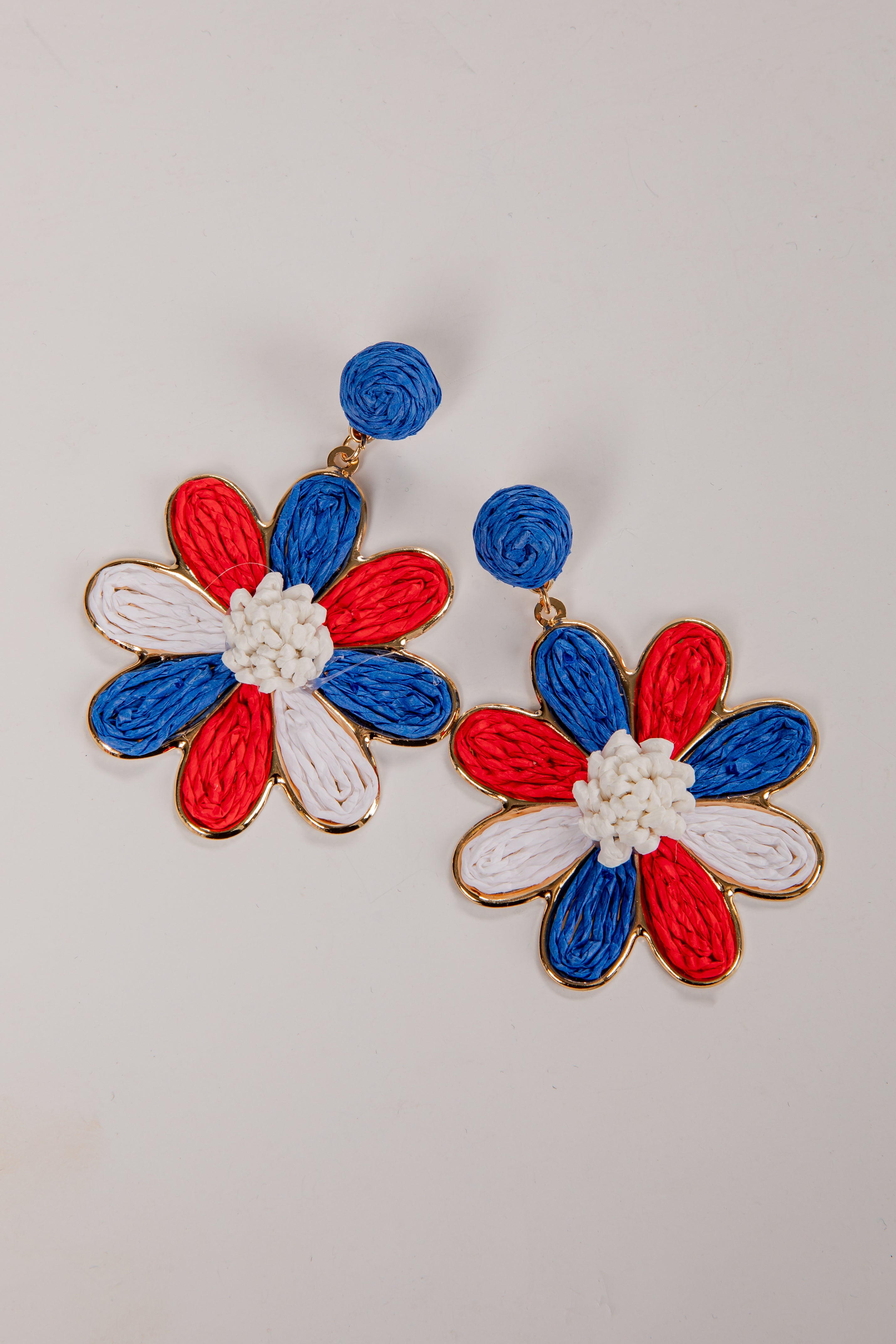 Flower-shaped earrings with red, white, and blue colors on a light gray background