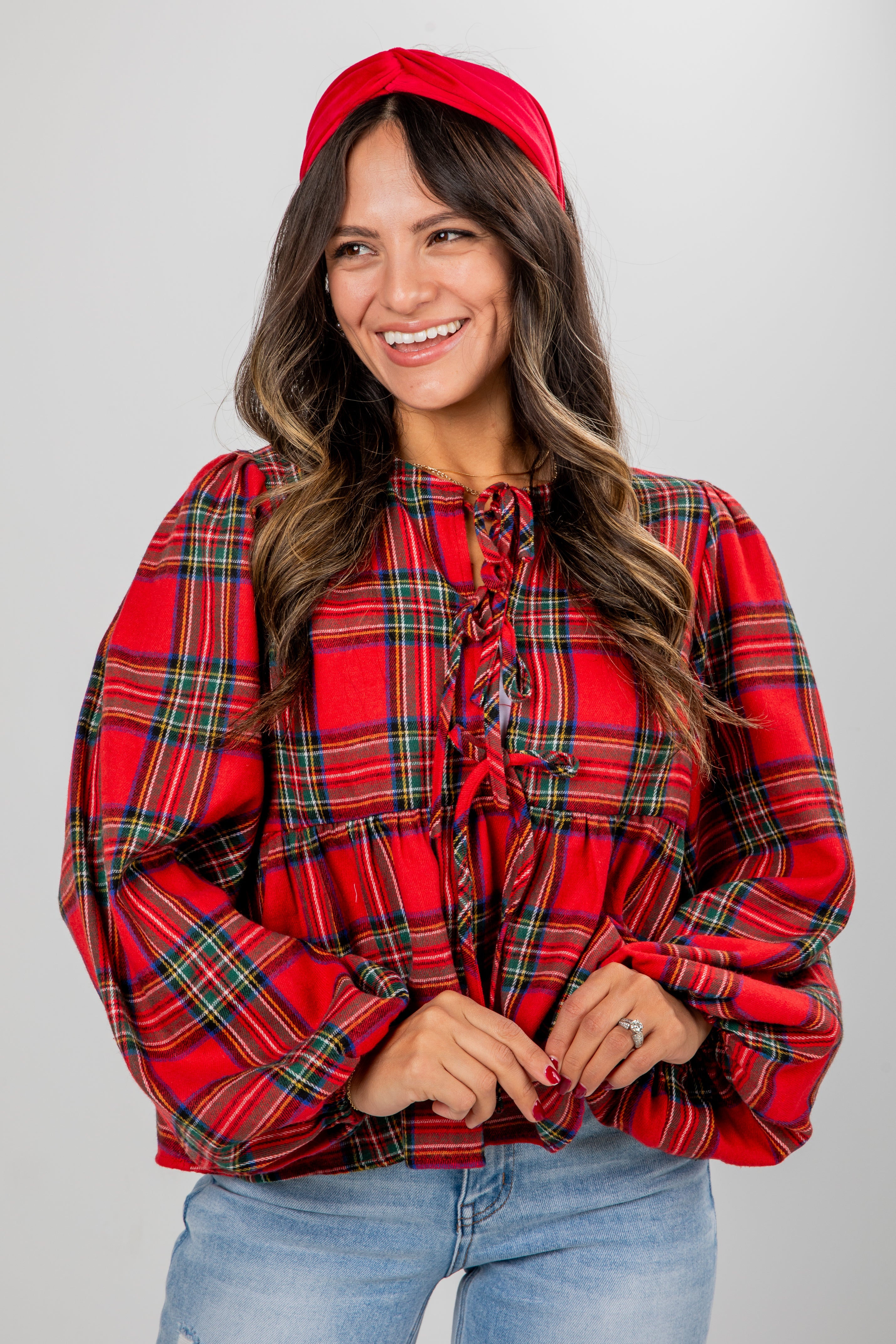 Woman wearing a red plaid blouse and red beret against a gray background