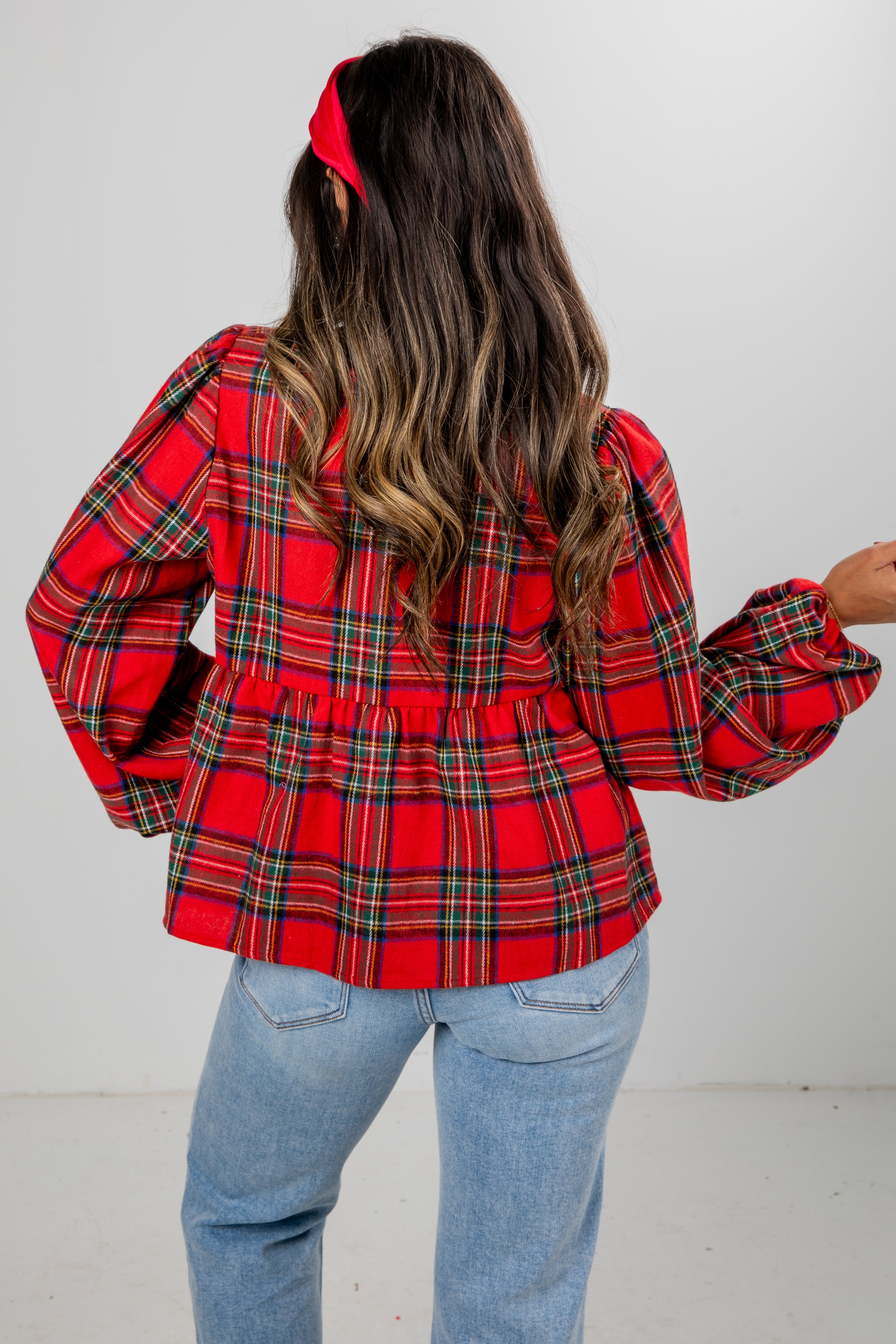 Person wearing a red plaid shirt and blue jeans with a white background