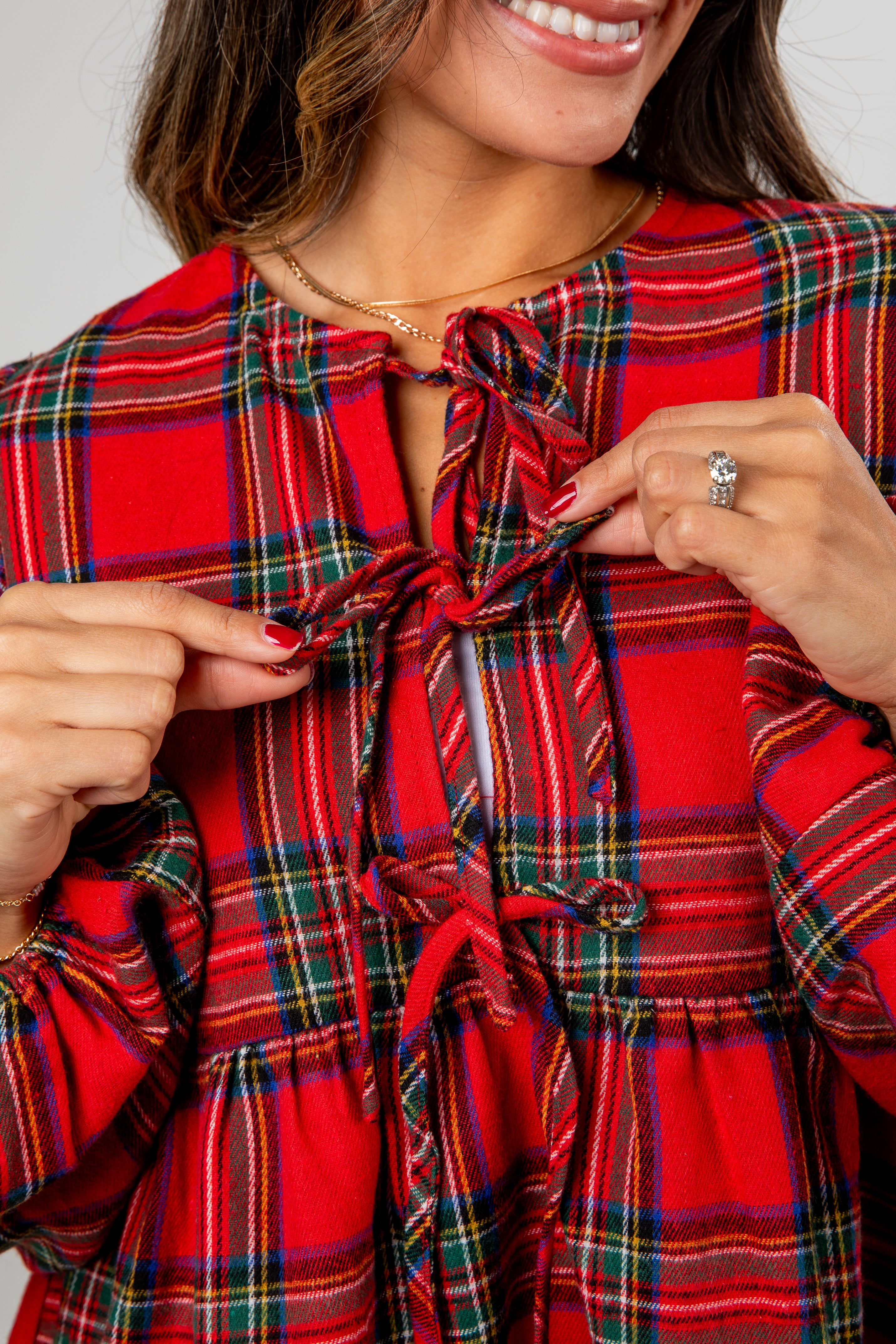 Woman wearing a red plaid dress pointing to the fabric