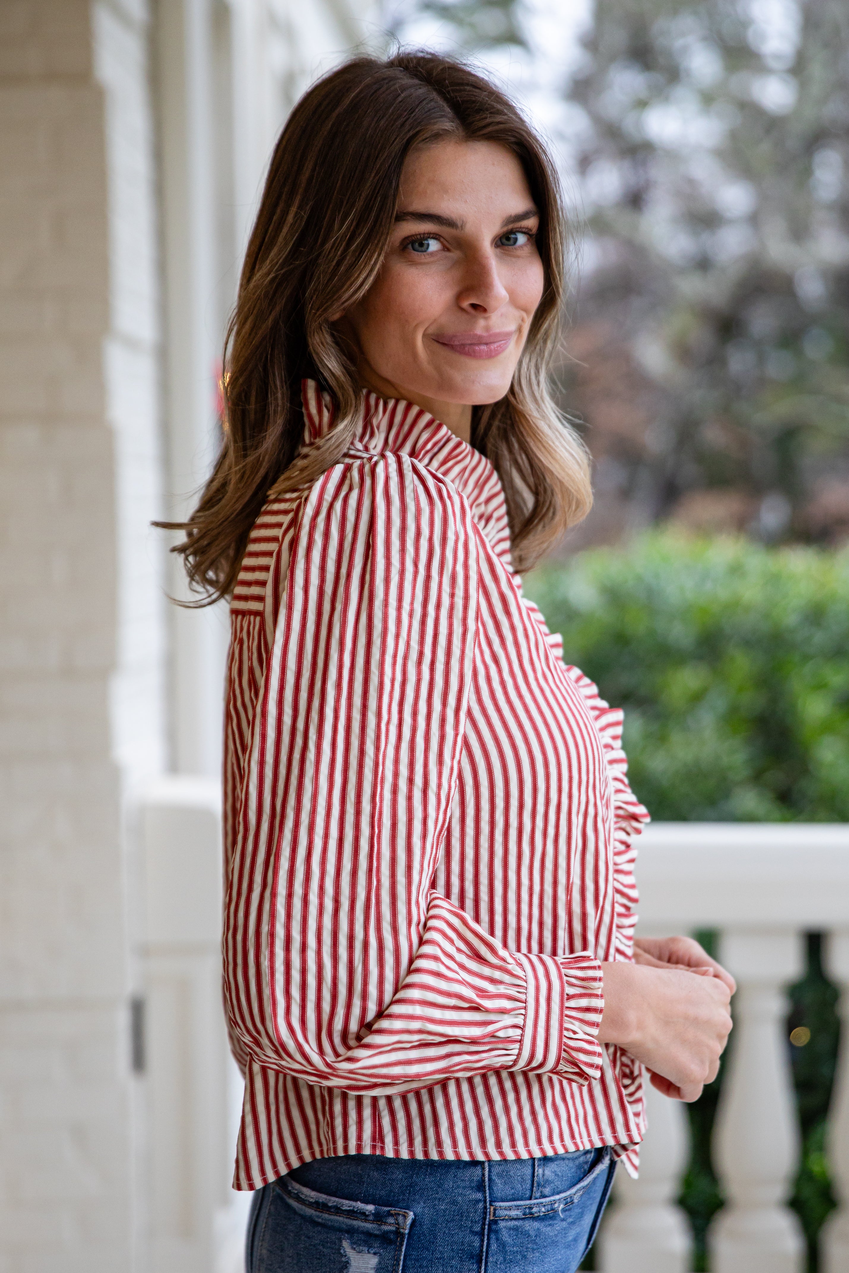 Woman wearing a red and white striped shirt with a blurred outdoor background