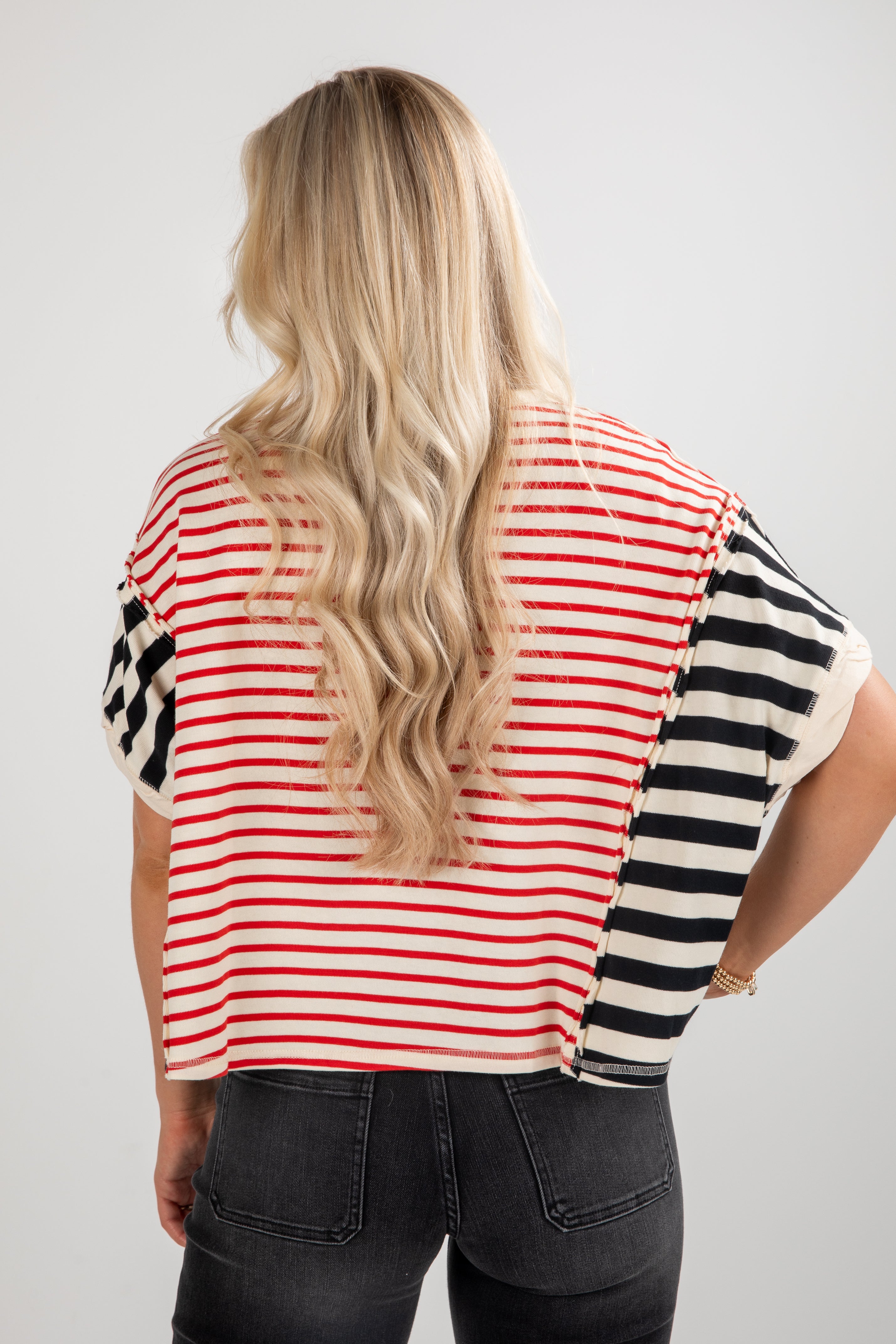 Person wearing a striped shirt with red, white, and black pattern on a plain background