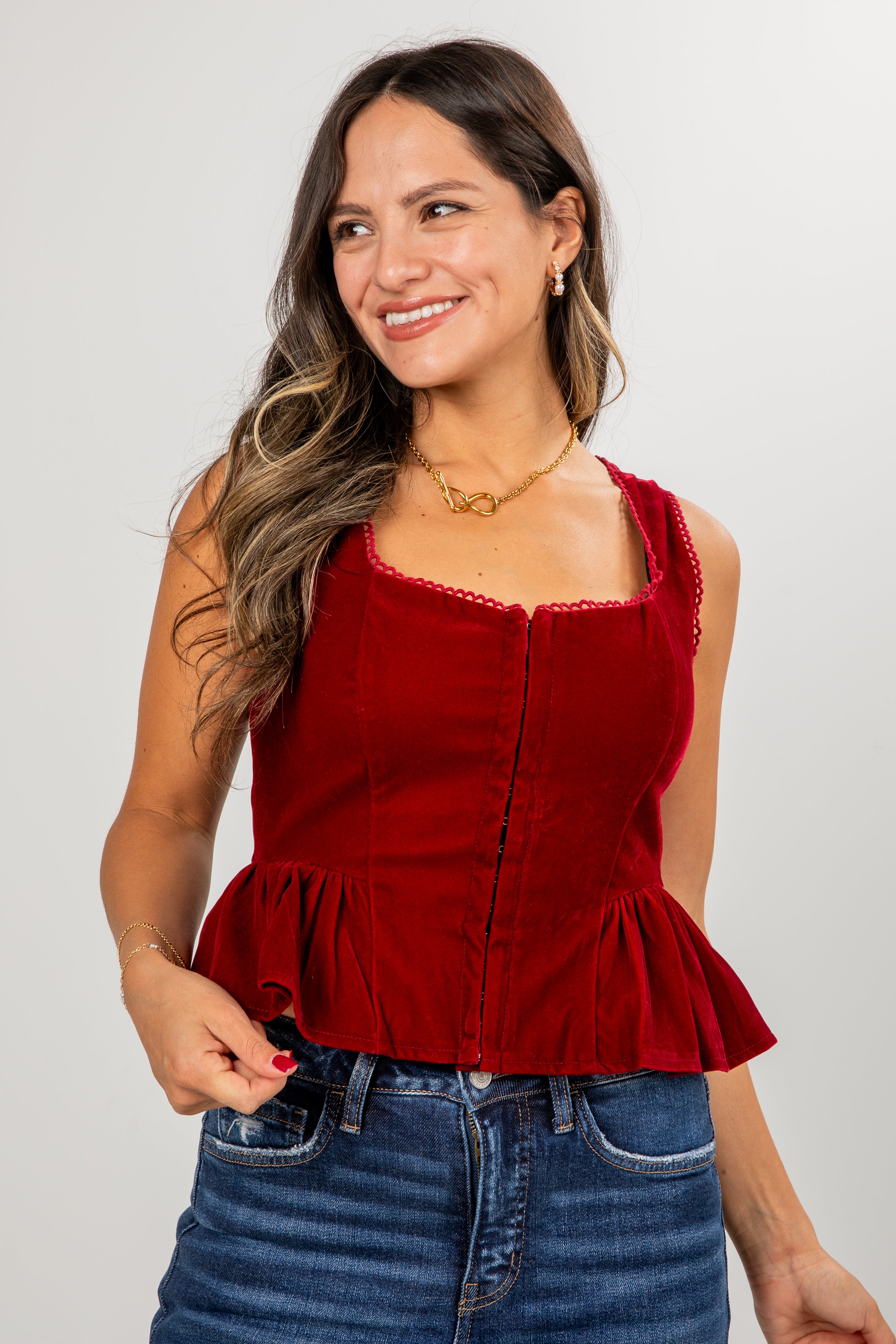 Woman wearing a red peplum top and blue jeans against a plain background