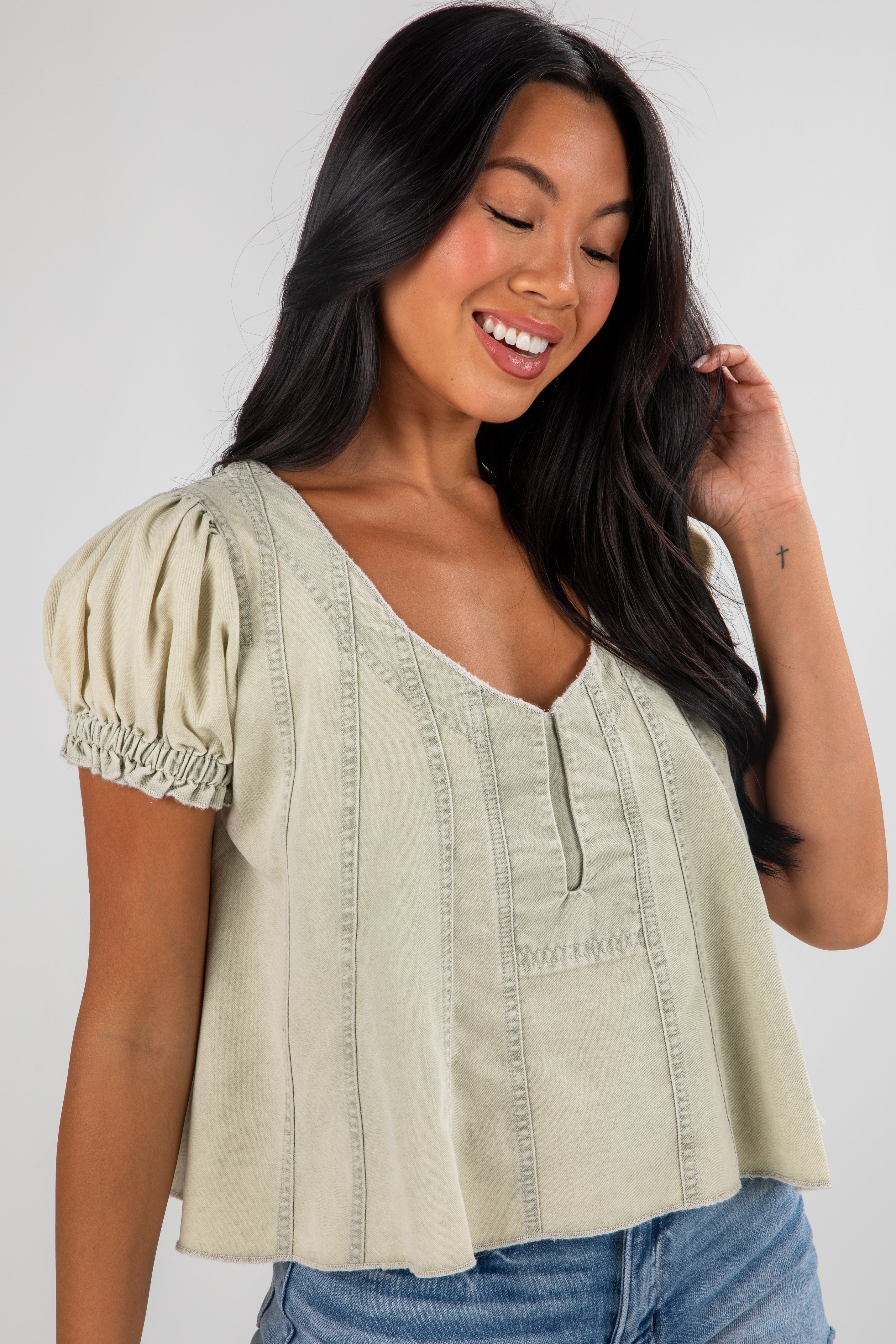 Woman wearing a light green blouse with puff sleeves against a white background