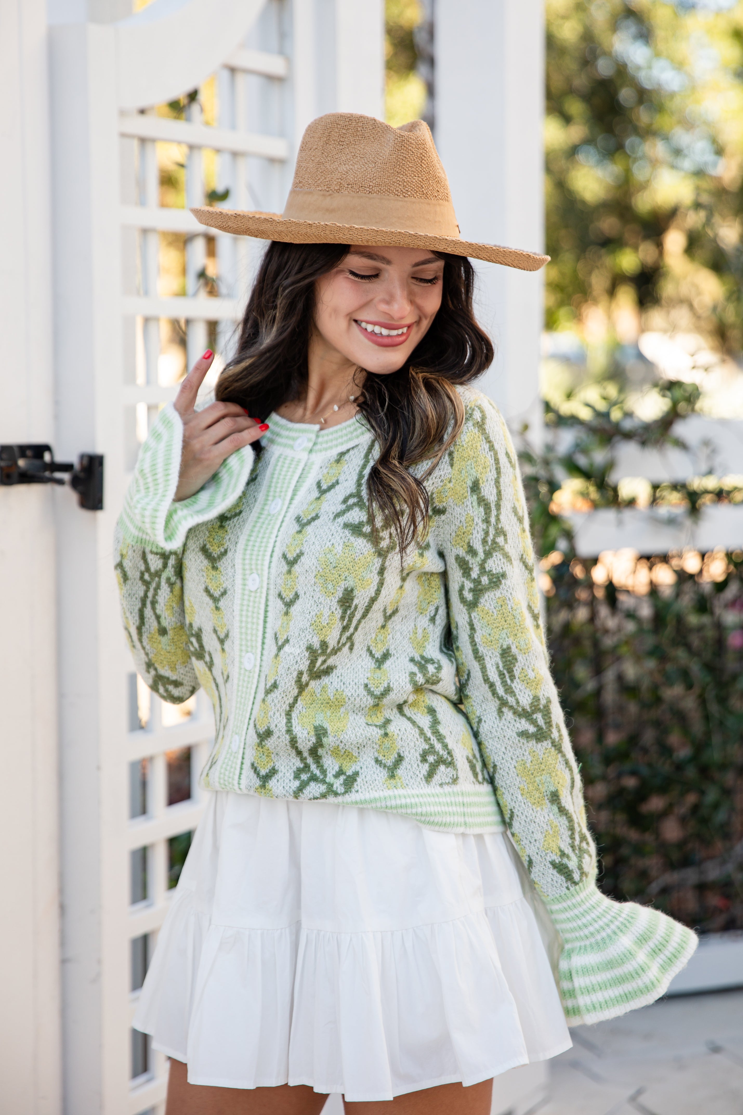 Woman wearing a green floral dress and beige hat outdoors