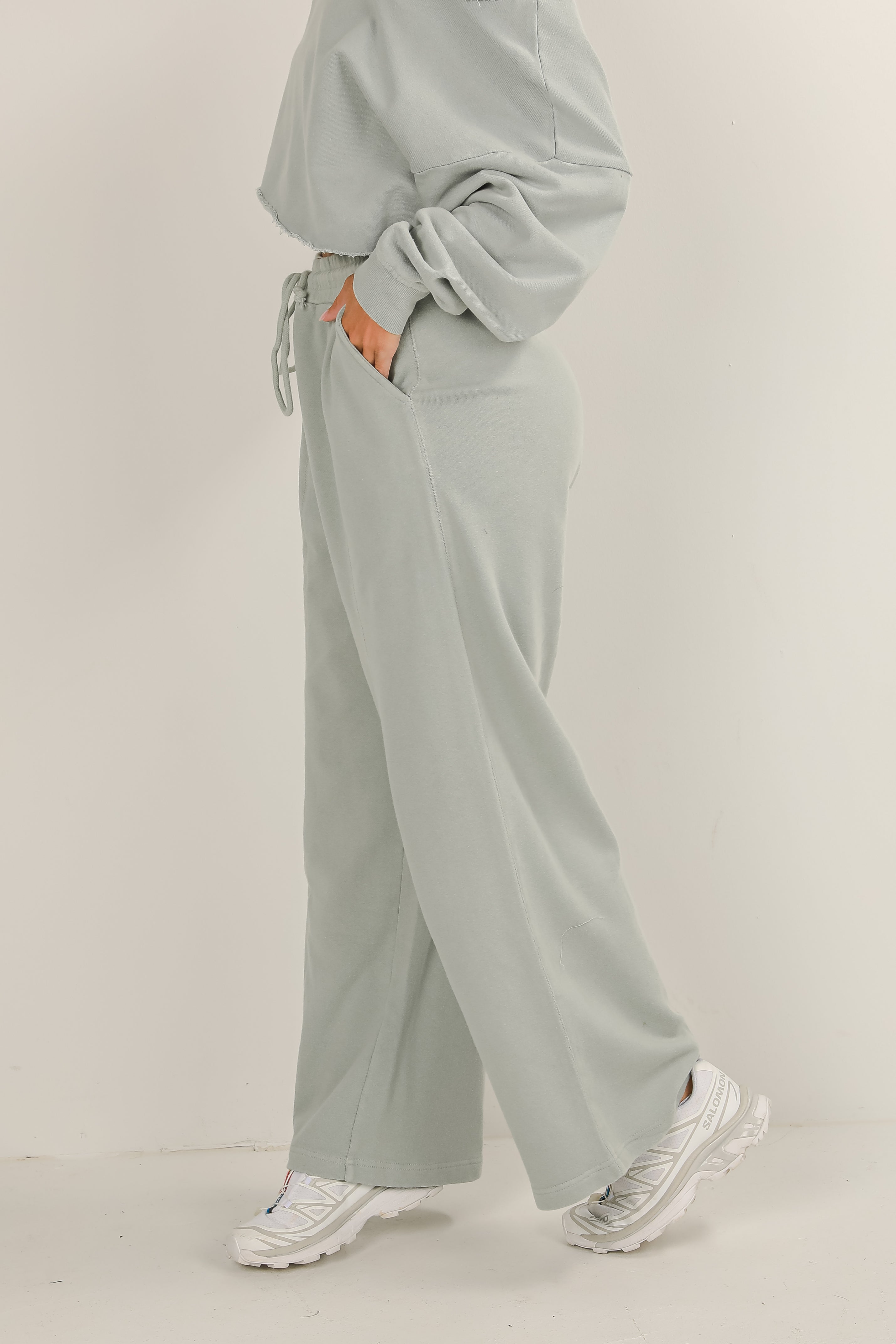 Person wearing a light gray outfit with wide-leg pants on a plain background