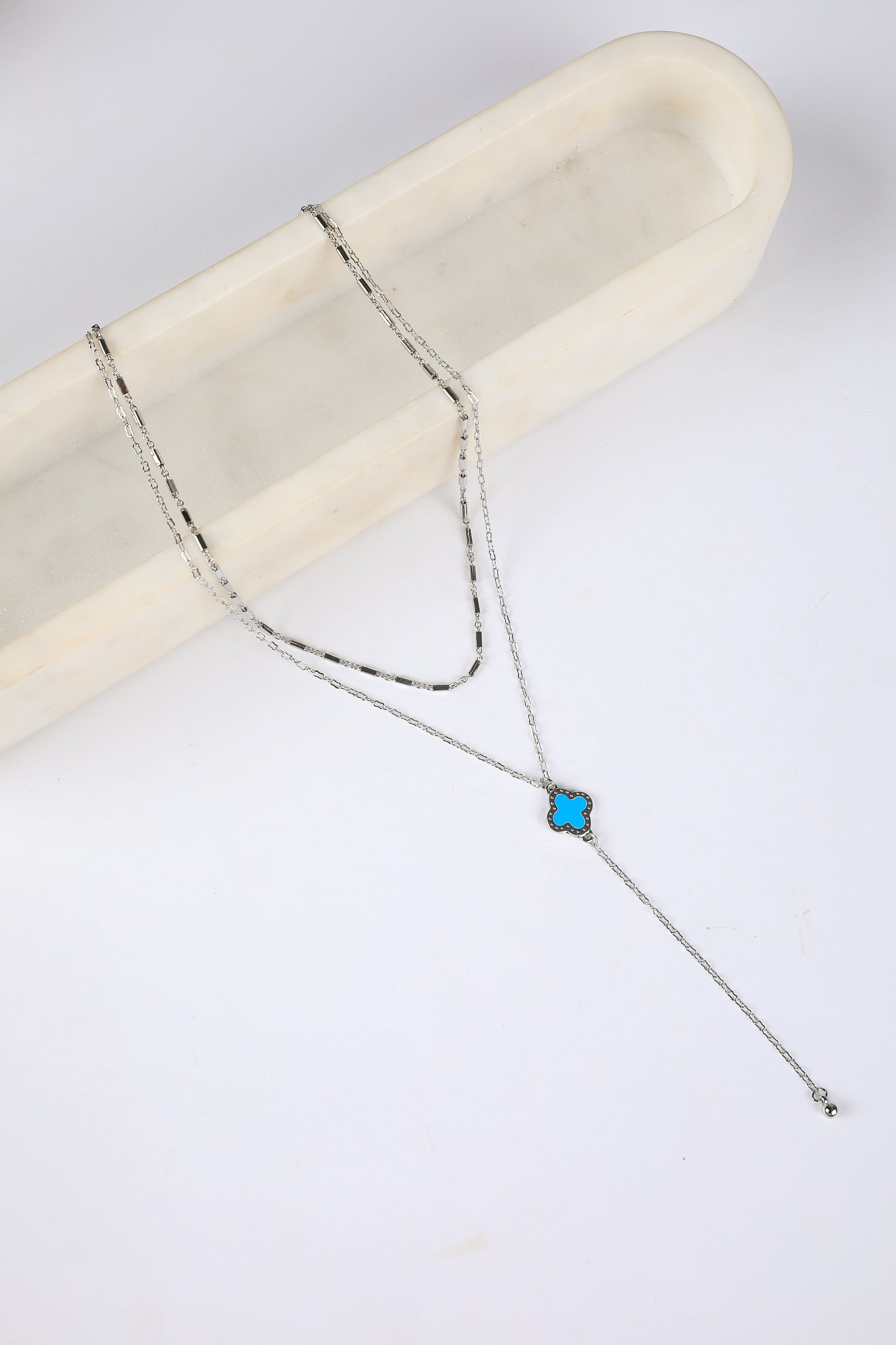 Silver necklace with a blue gemstone on a white background