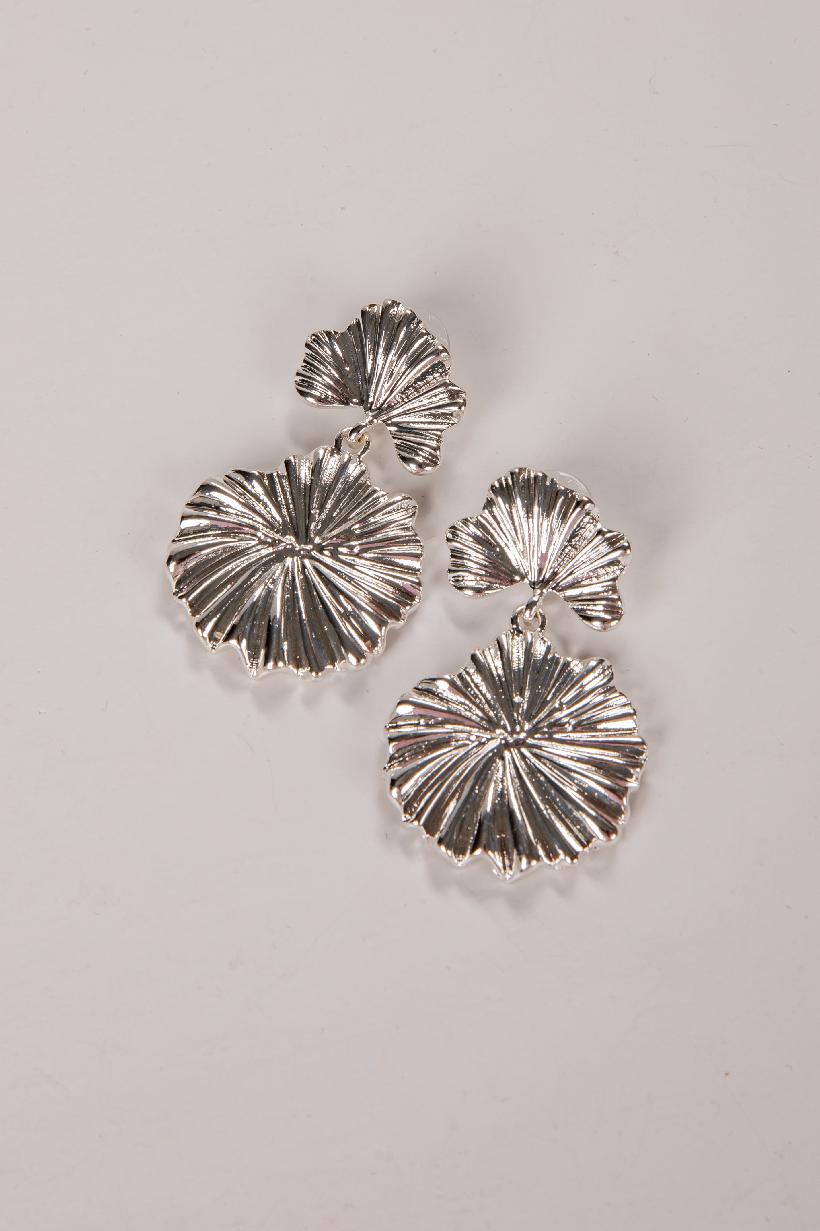 Silver earrings with a textured design on a light gray background