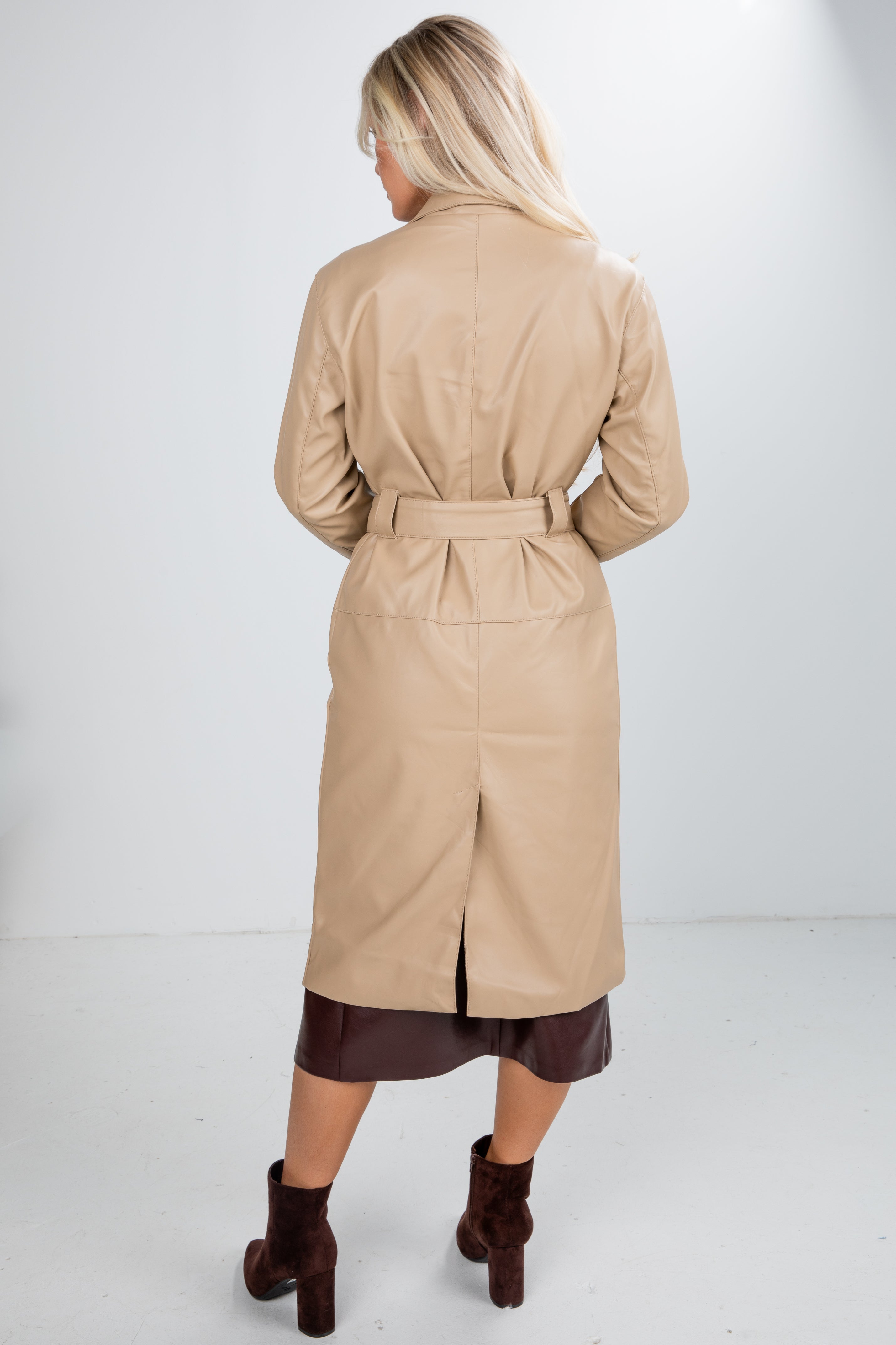 Person wearing a beige trench coat on a white background