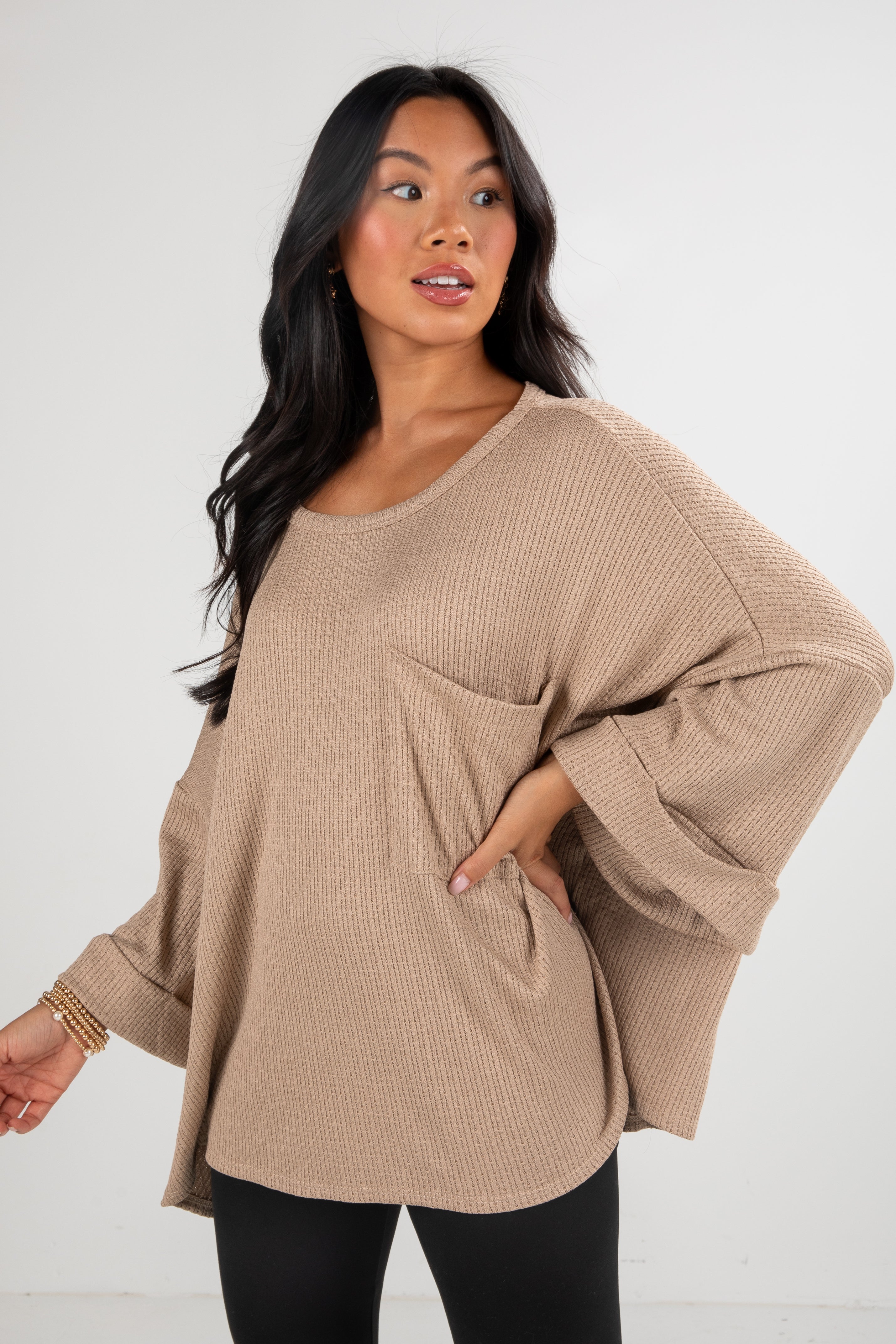 Woman wearing a beige sweater against a white background