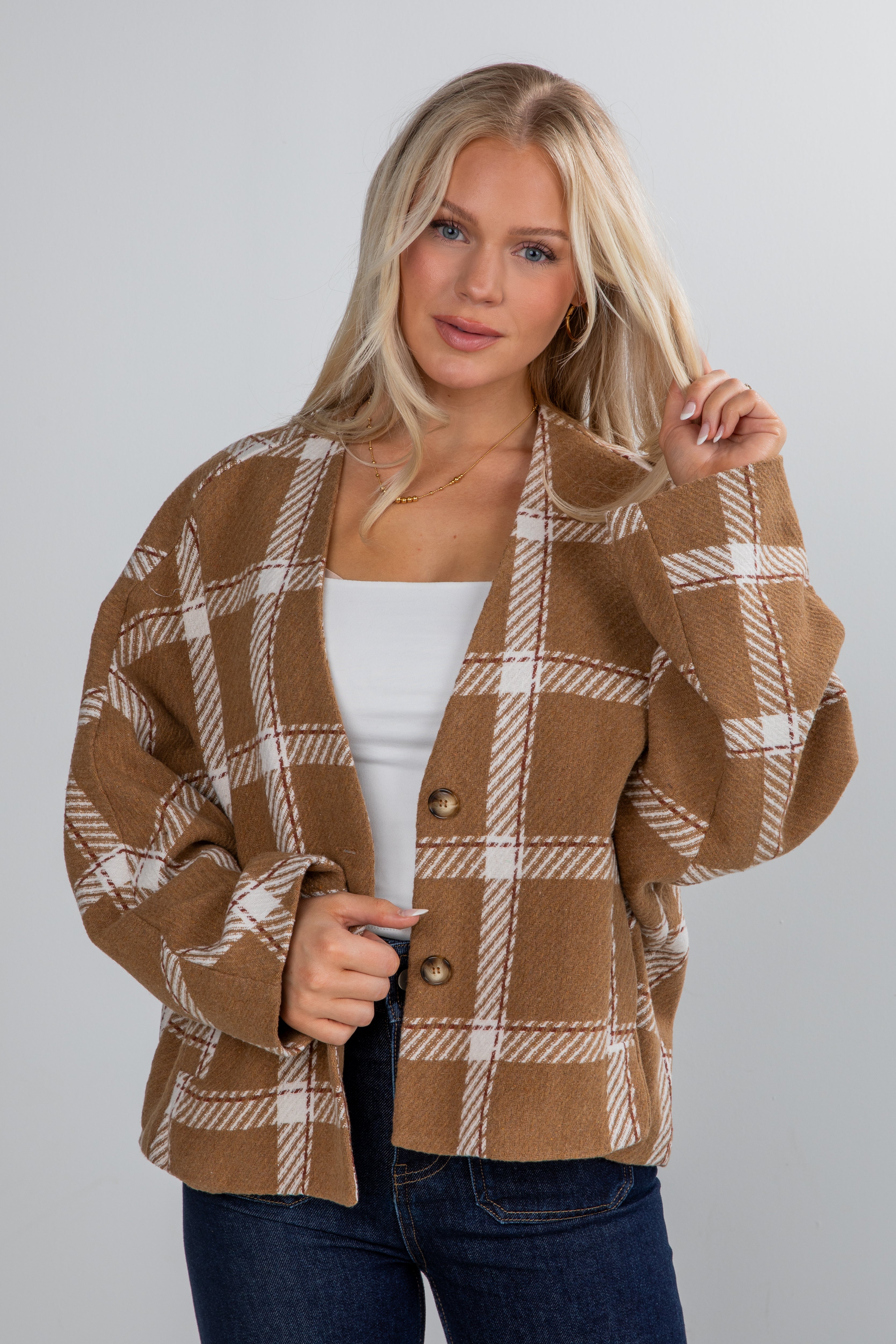 Woman wearing a brown plaid jacket on a plain background