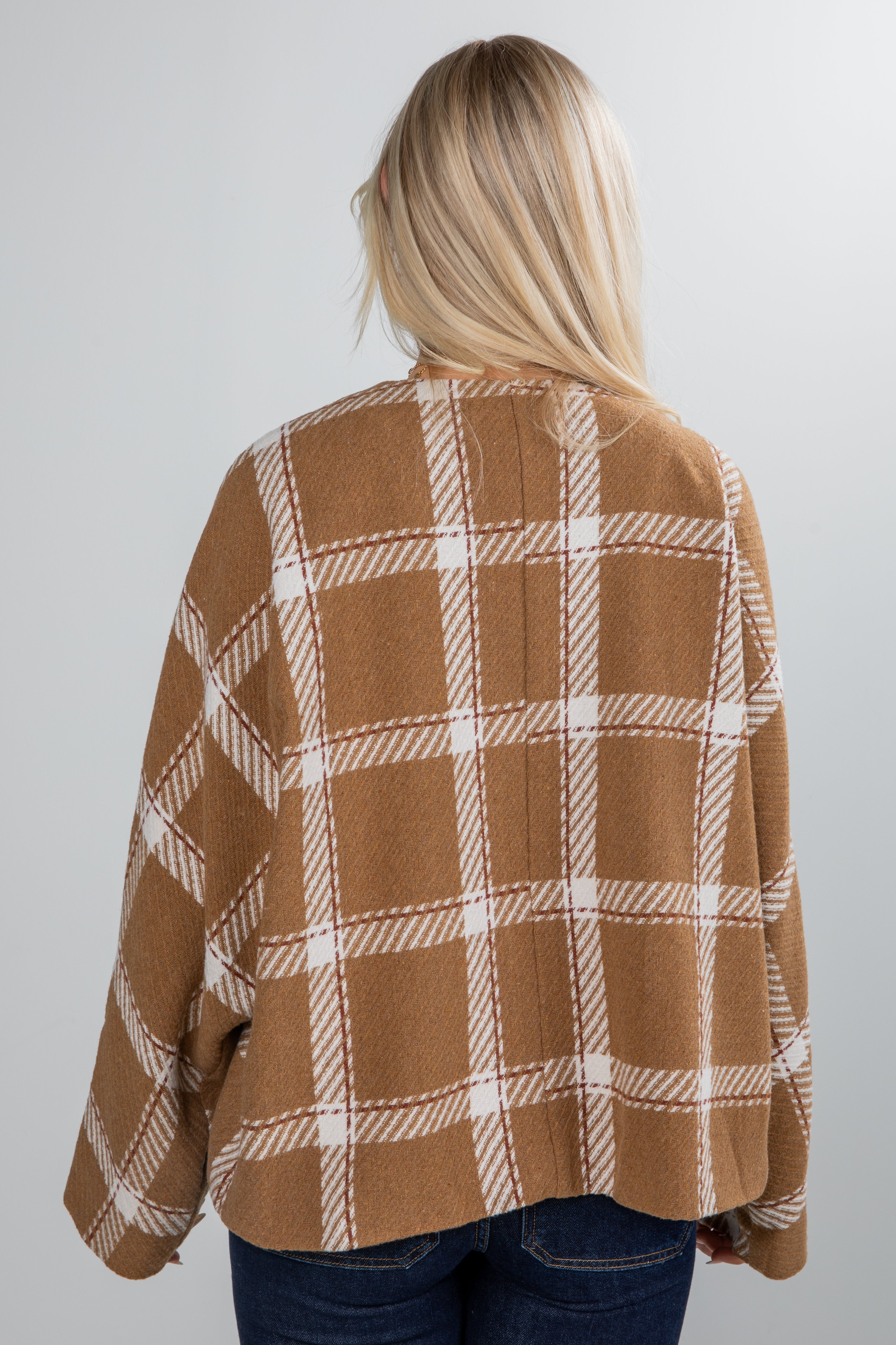 Person wearing a brown and white plaid shirt against a plain background