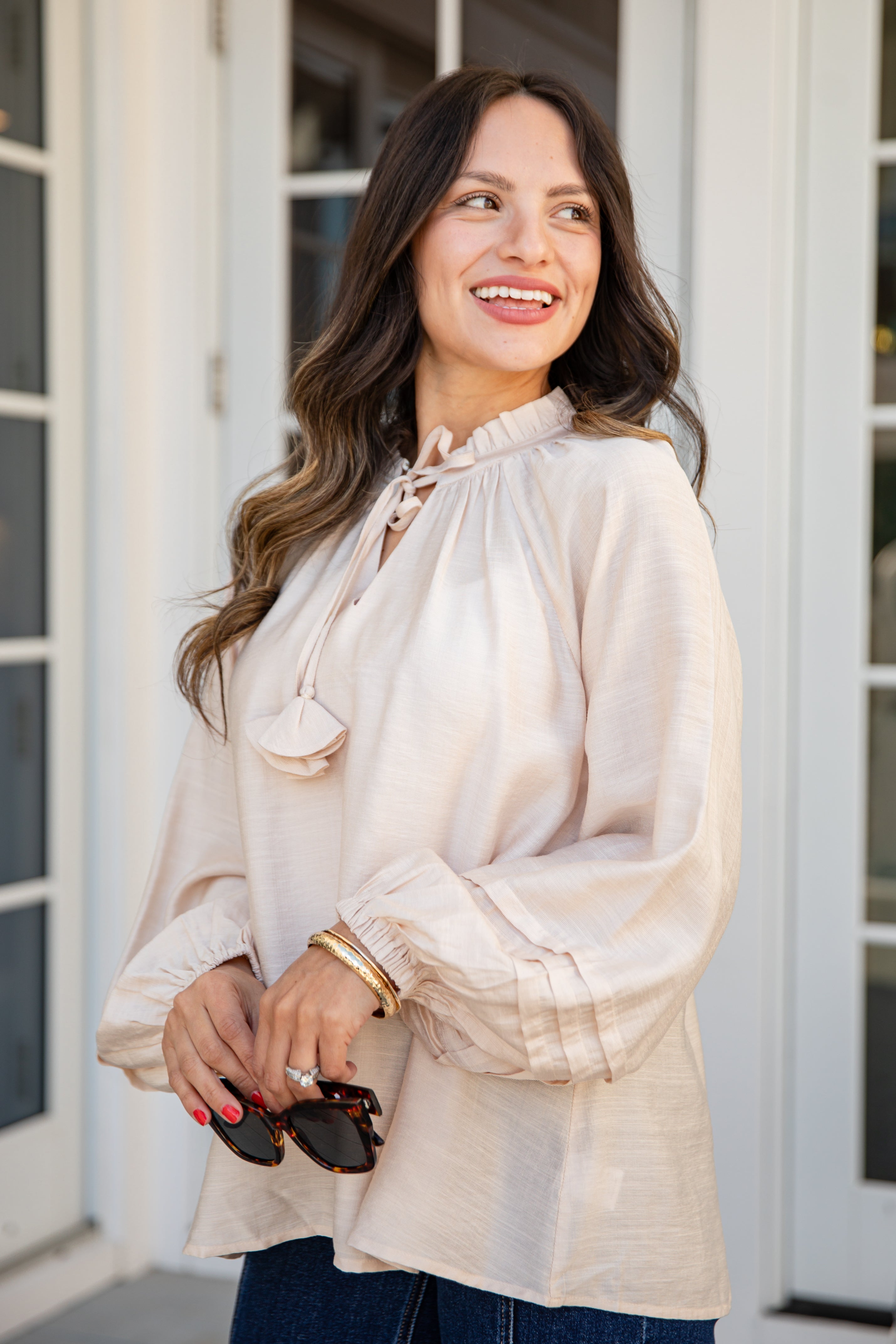 Woman wearing a beige blouse standing outside a building