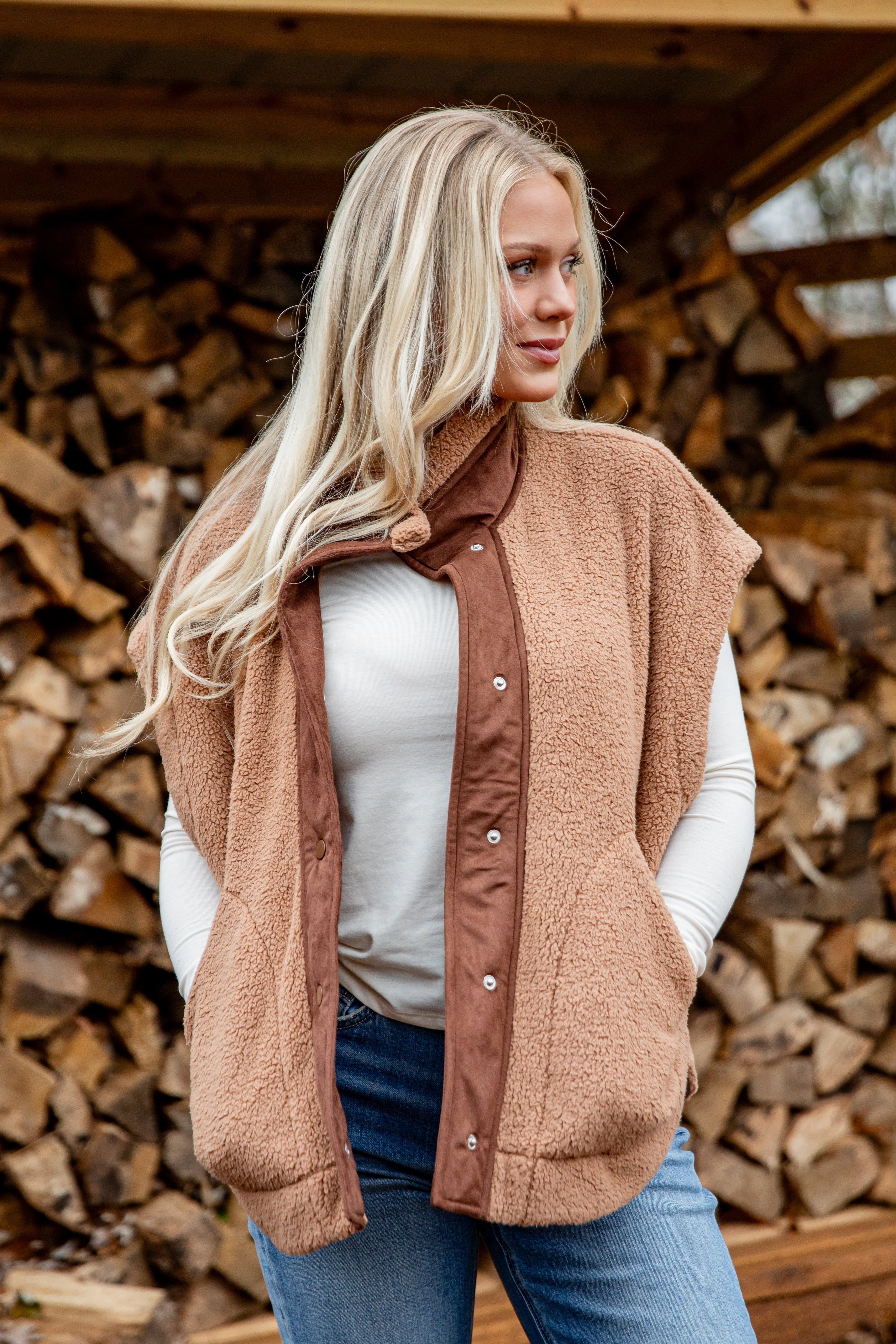 Woman wearing a brown vest over a white shirt with a wooden background