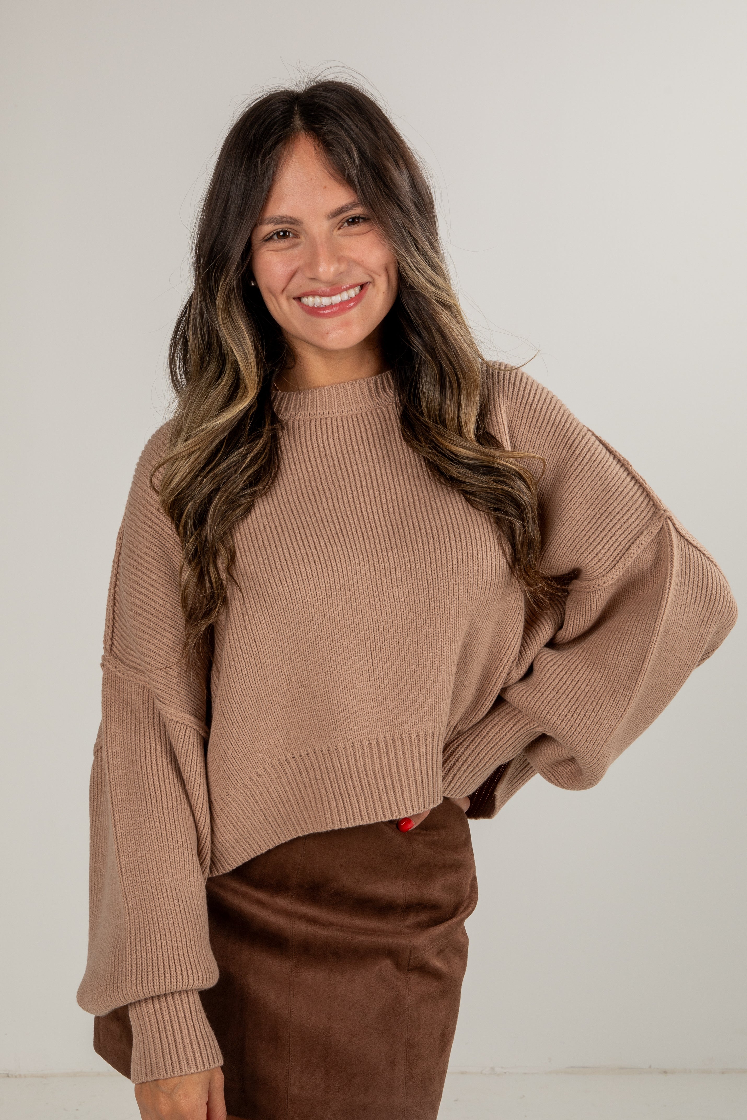 Woman wearing a brown sweater and pants against a white background