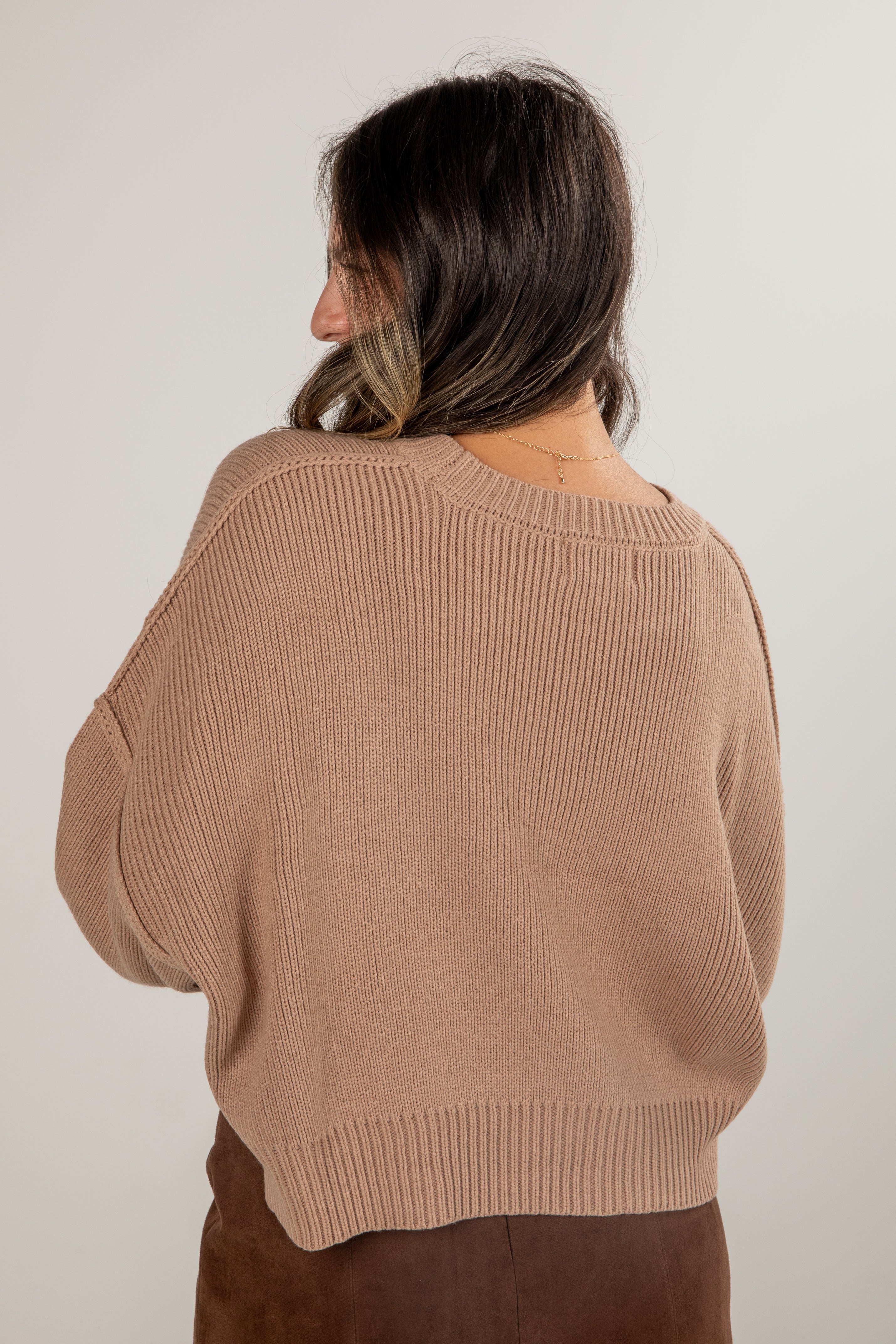 Woman wearing a brown sweater against a plain background