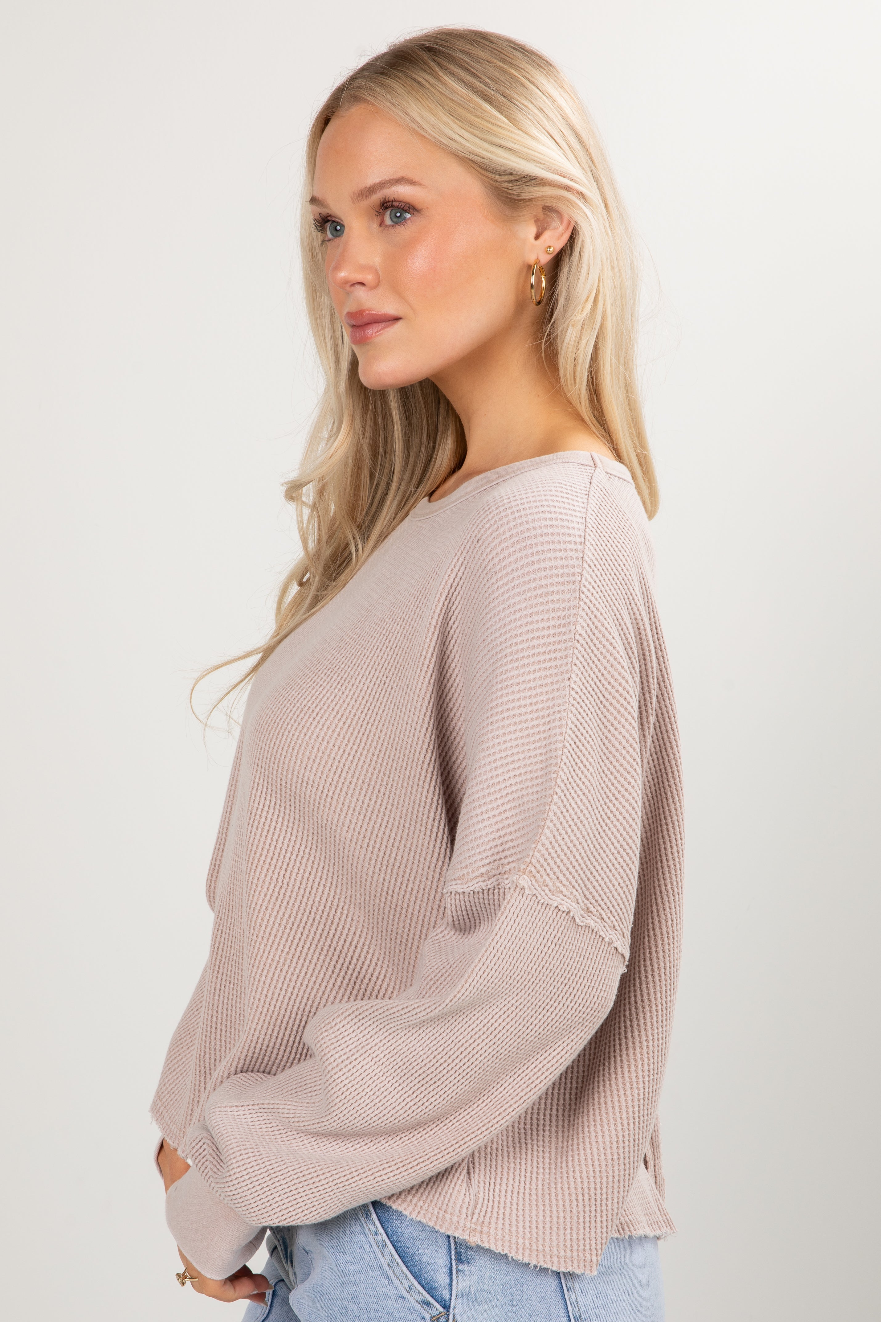 Woman wearing a light pink sweater with a plain background