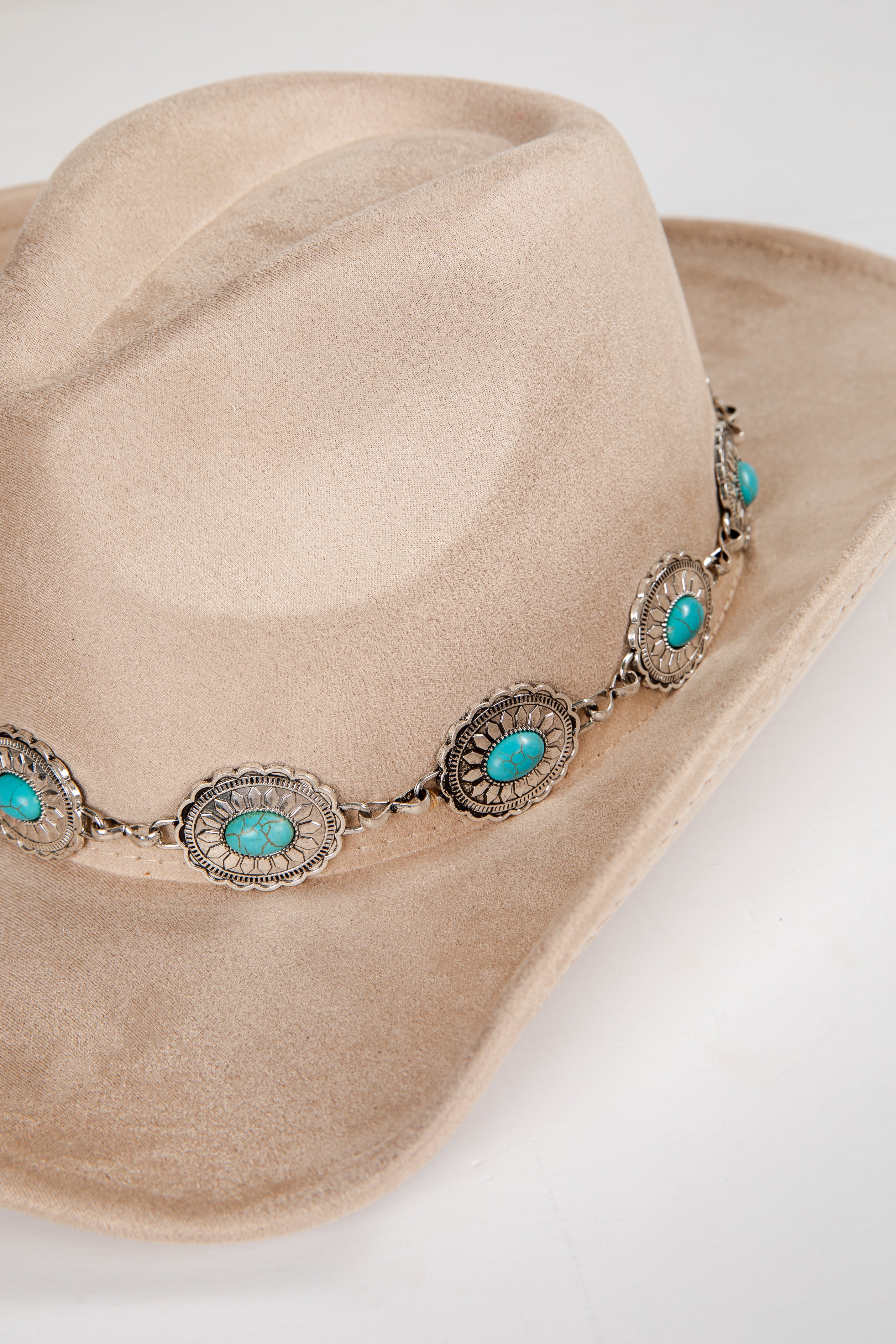 Beige cowboy hat with turquoise stone and silver band on a white background