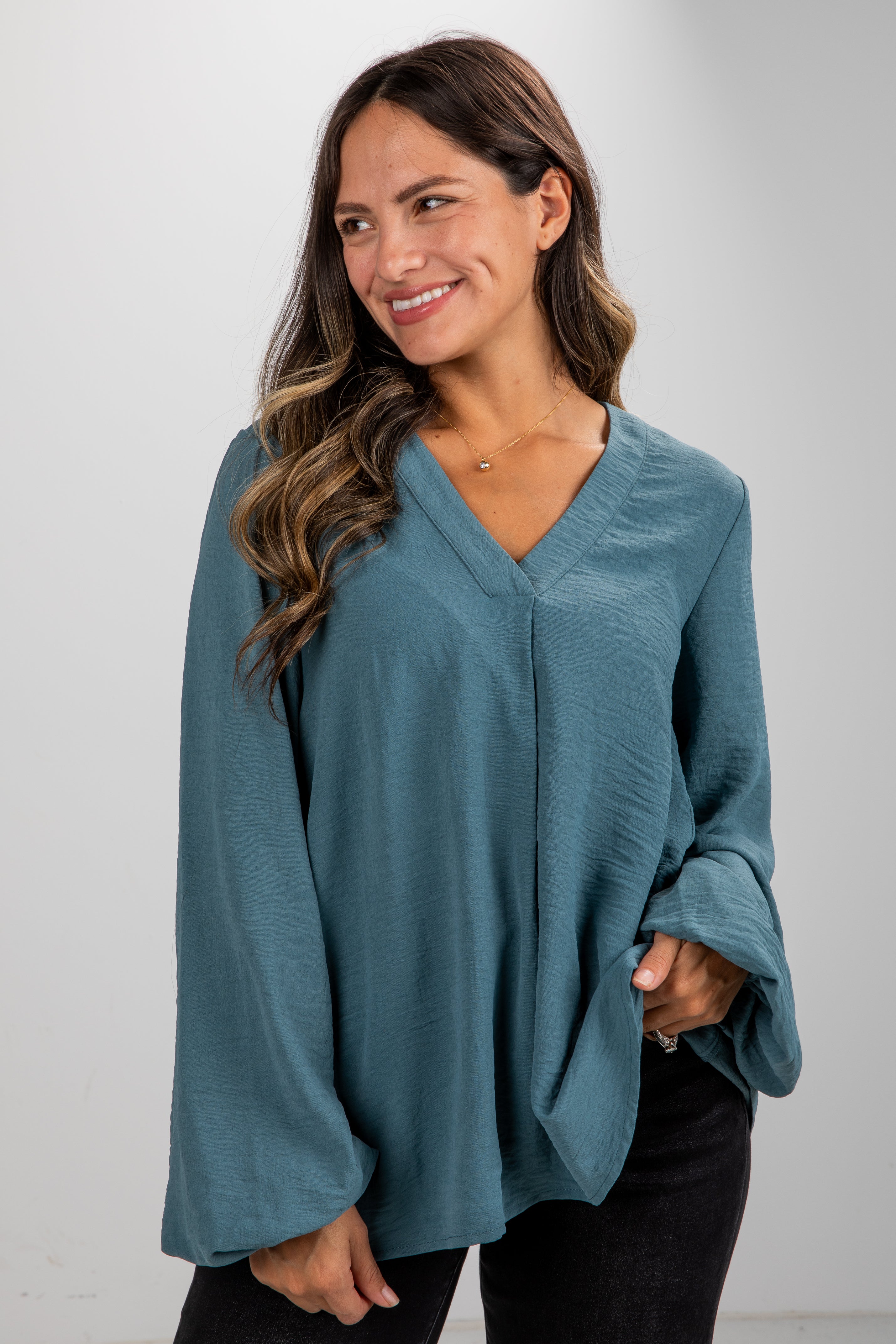 Woman wearing a teal sweater against a plain background