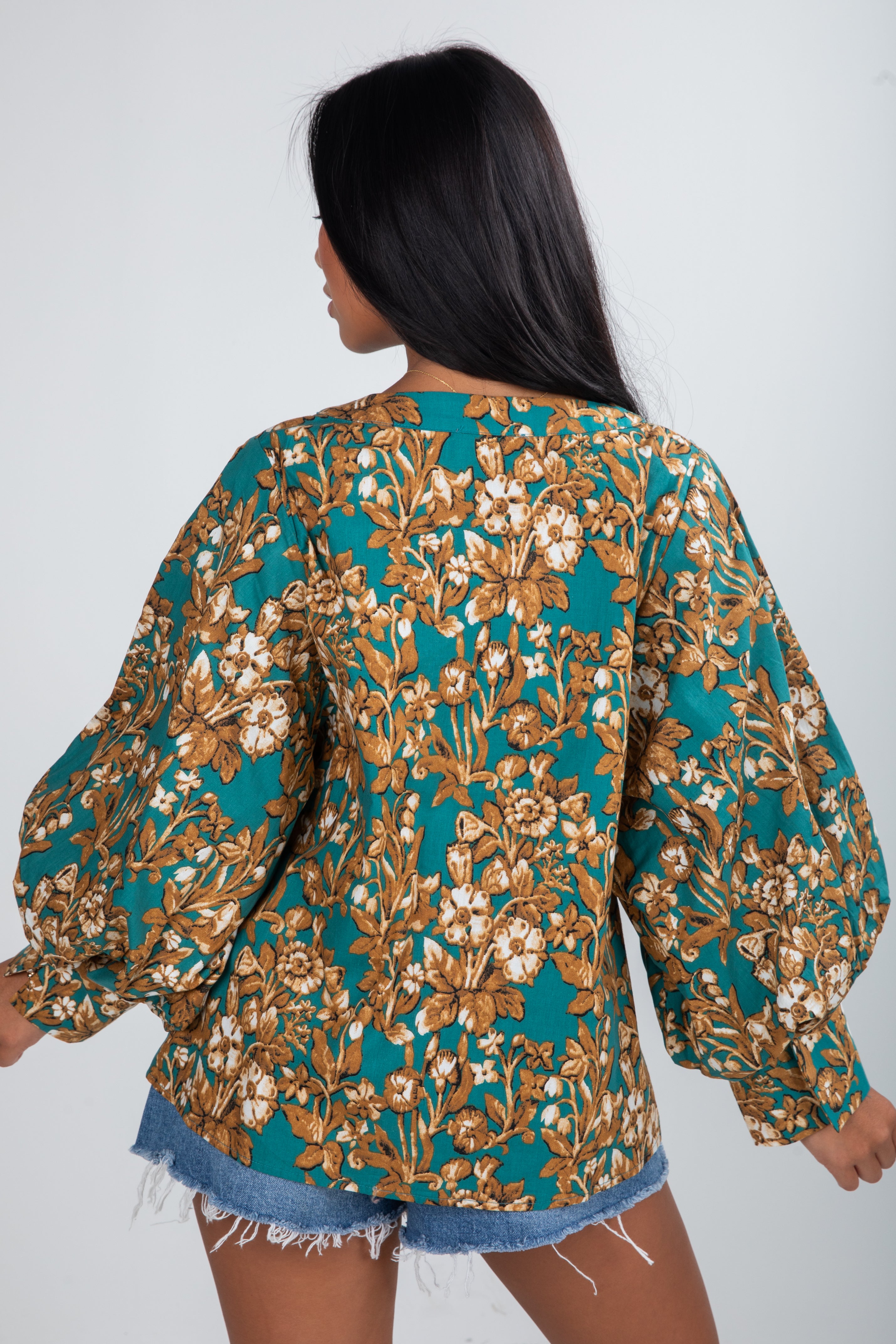 Woman wearing a floral patterned top with long sleeves on a white background