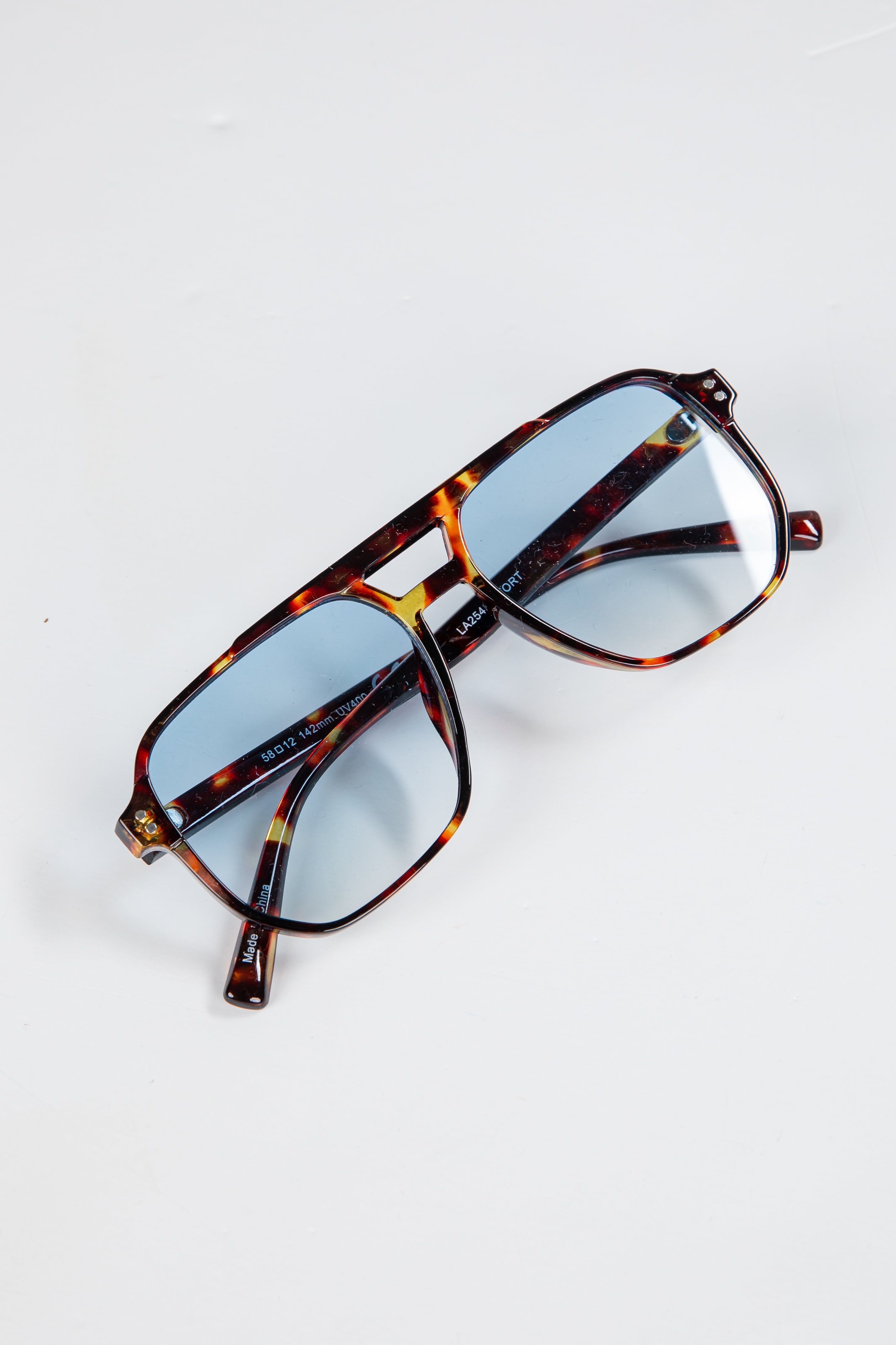 Tortoiseshell sunglasses with blue lenses on a white background