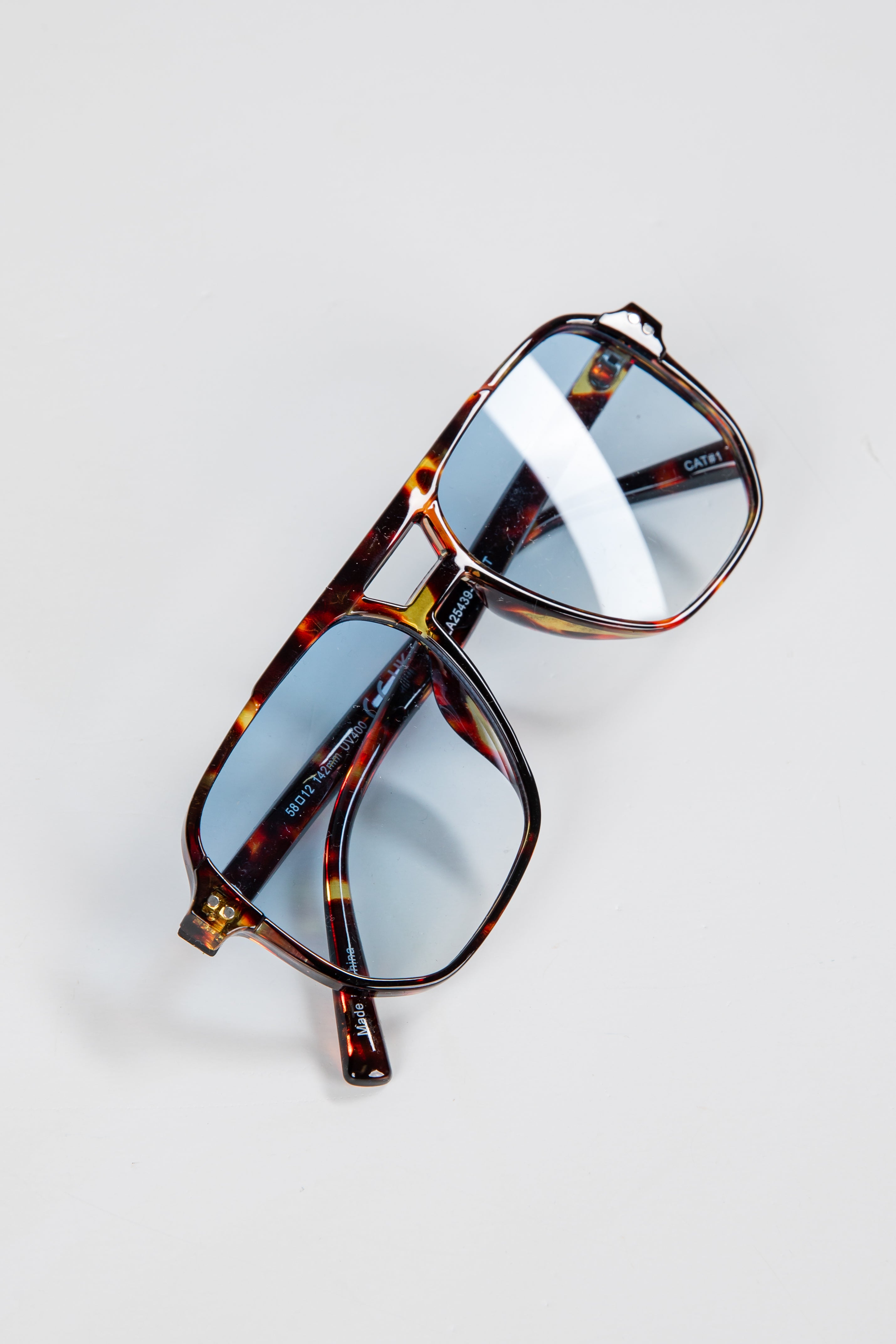 Tortoiseshell sunglasses with reflective lenses on a light gray background