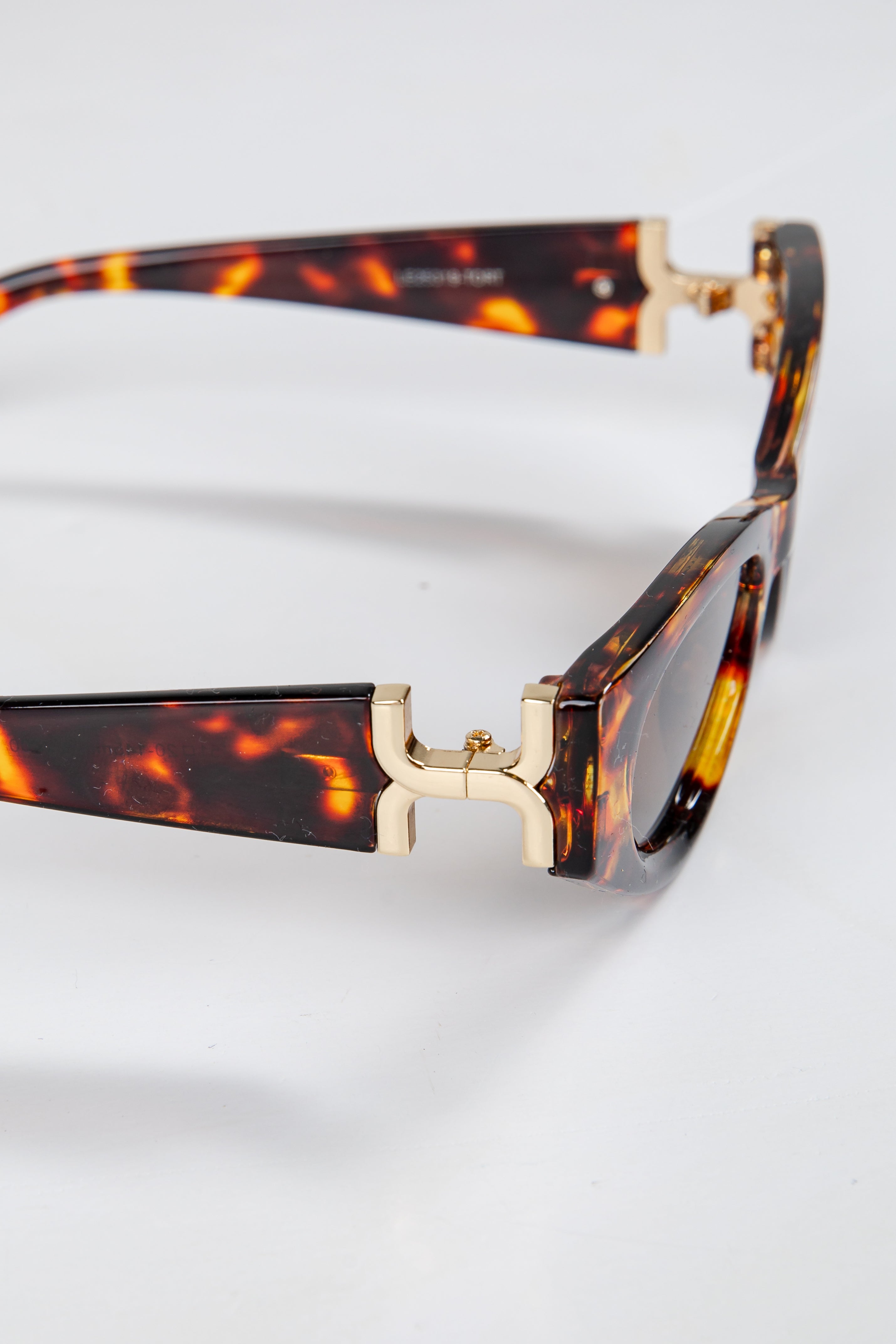 Tortoiseshell sunglasses with gold accents on a white background
