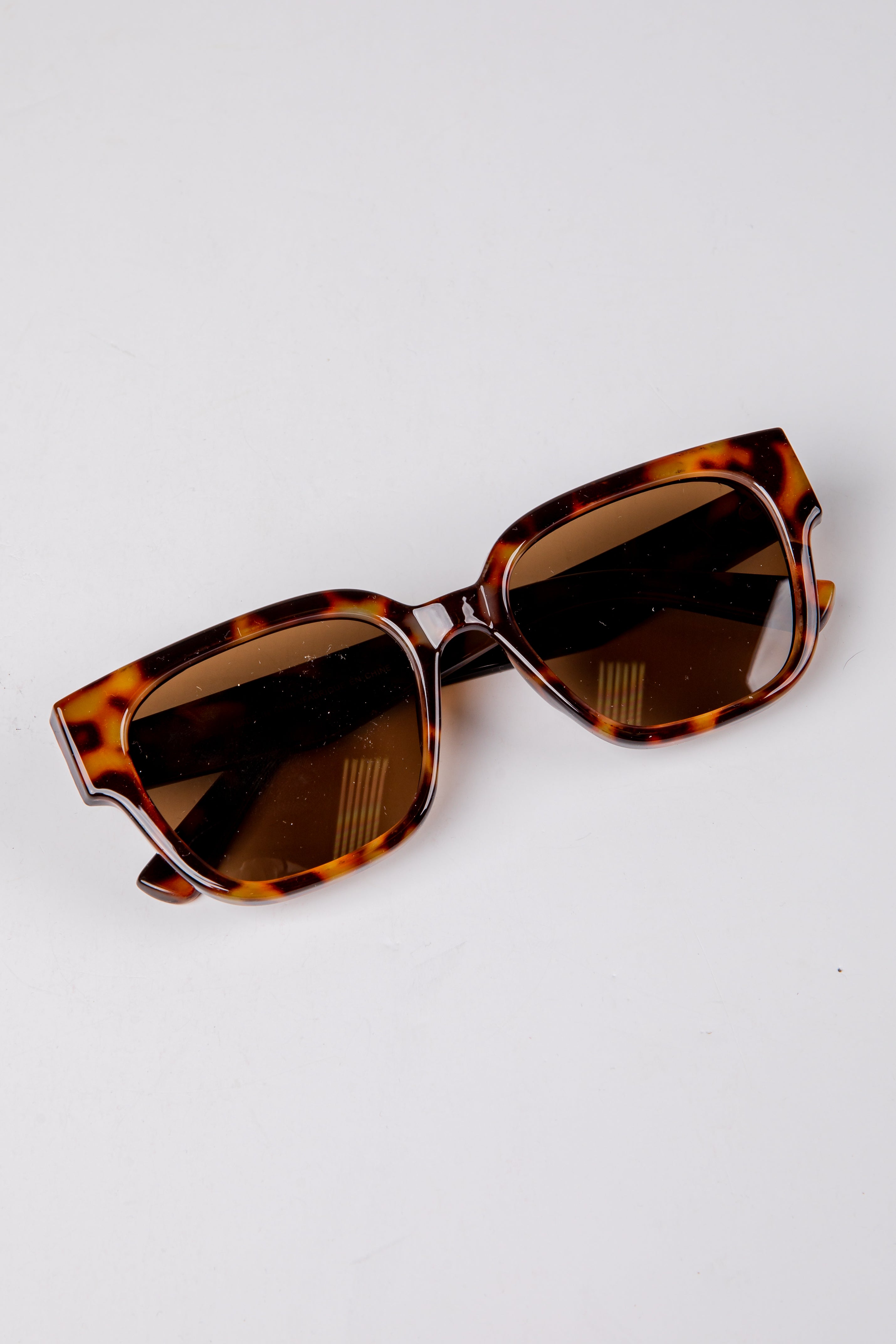 Tortoiseshell sunglasses with brown lenses on a white background