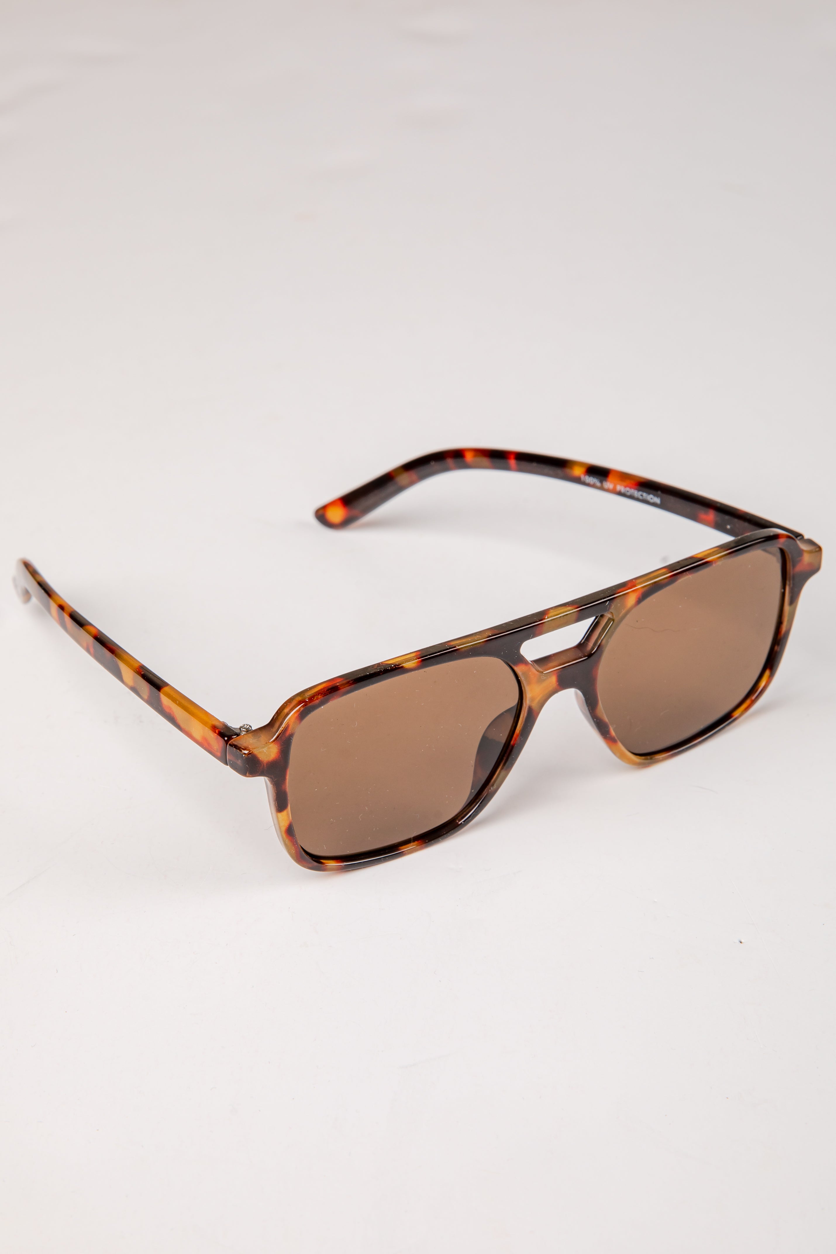 Sunglasses with tortoiseshell frame and brown lenses on a white background